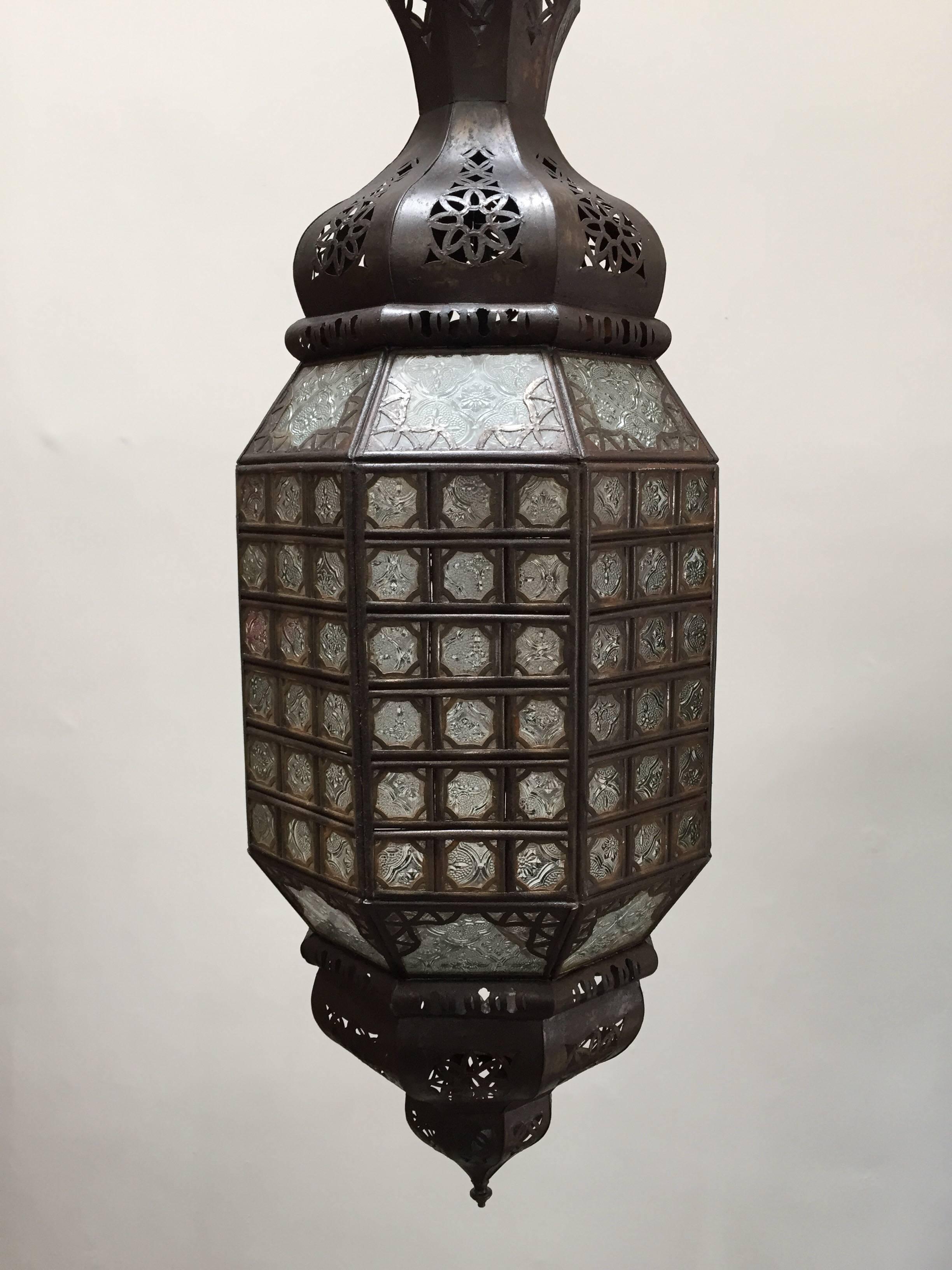 Stylish handcrafted Moroccan pendant lantern with clear molded glass and metal with an antique bronze finish.
Moorish style glass pendant with dozen of small cut-glass with filigree metal designs in diamond shape.
This Moroccan light fixture is