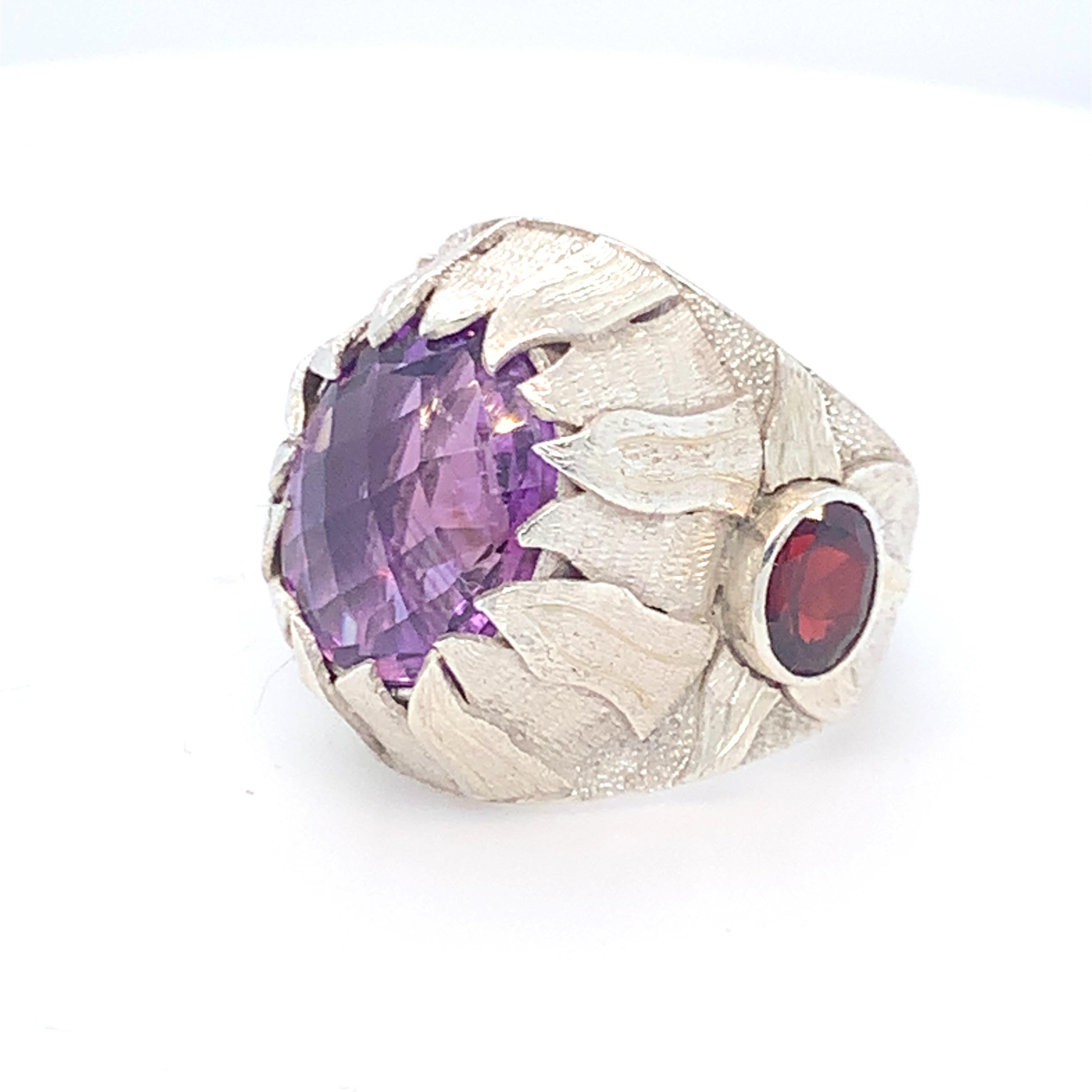 Oval natural Amethyst is the center stone of this cocktail ring. Checkerboard cut Amethyst is framed by artistically crafted flames of fire which makes it an exquisite ring . Small round garnets are set on the sides which enhances the beauty of this