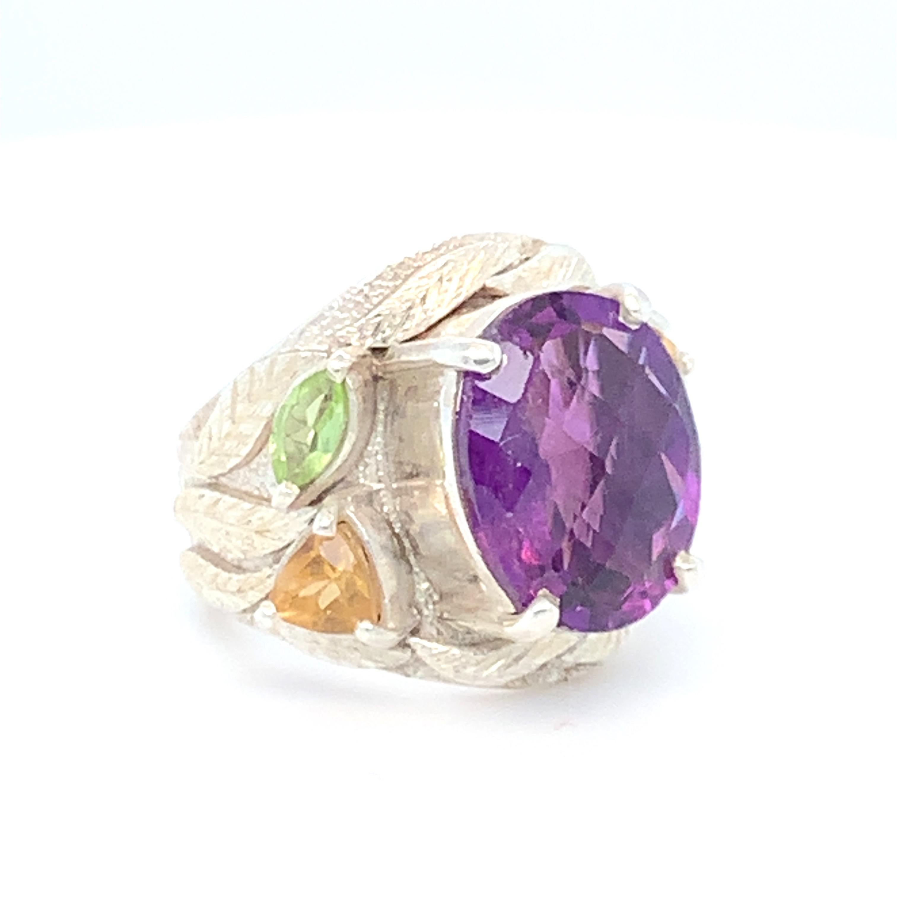Natural checkerboard cut Amethyst is the center stone of this vibrant cocktail ring. Trillion citrine, marquise peridot and garnet with intricately crafted leaves on each sides enhances the beauty of this ring. Set in sterling silver and carefully