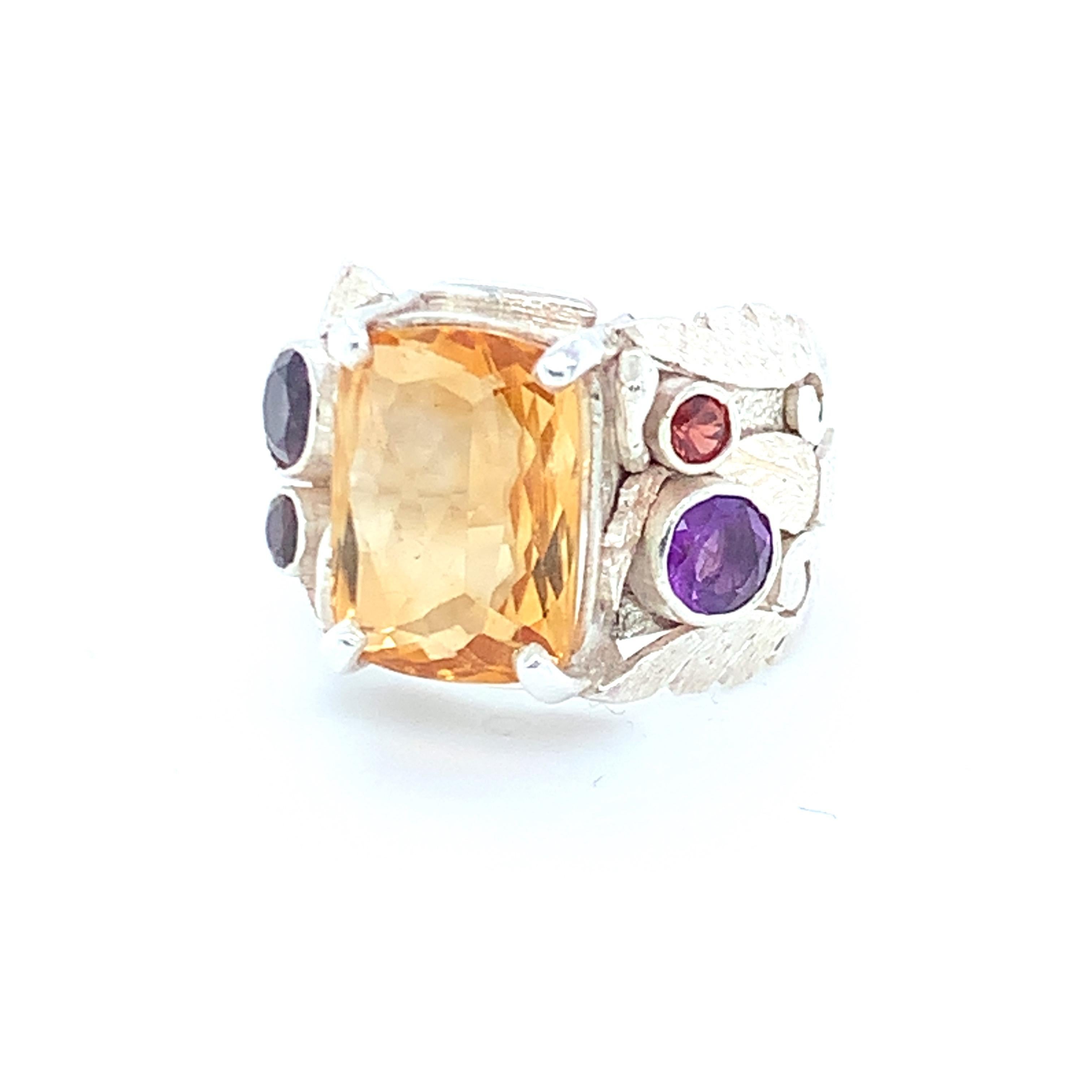 Radiant cut citrine is the main stone of this stunning, one of a kind cocktail ring. Round amethyst and garnet is used as accent stones on the sides with the multi layered artistic motifs. Set in sterling silver and carefully crafted with