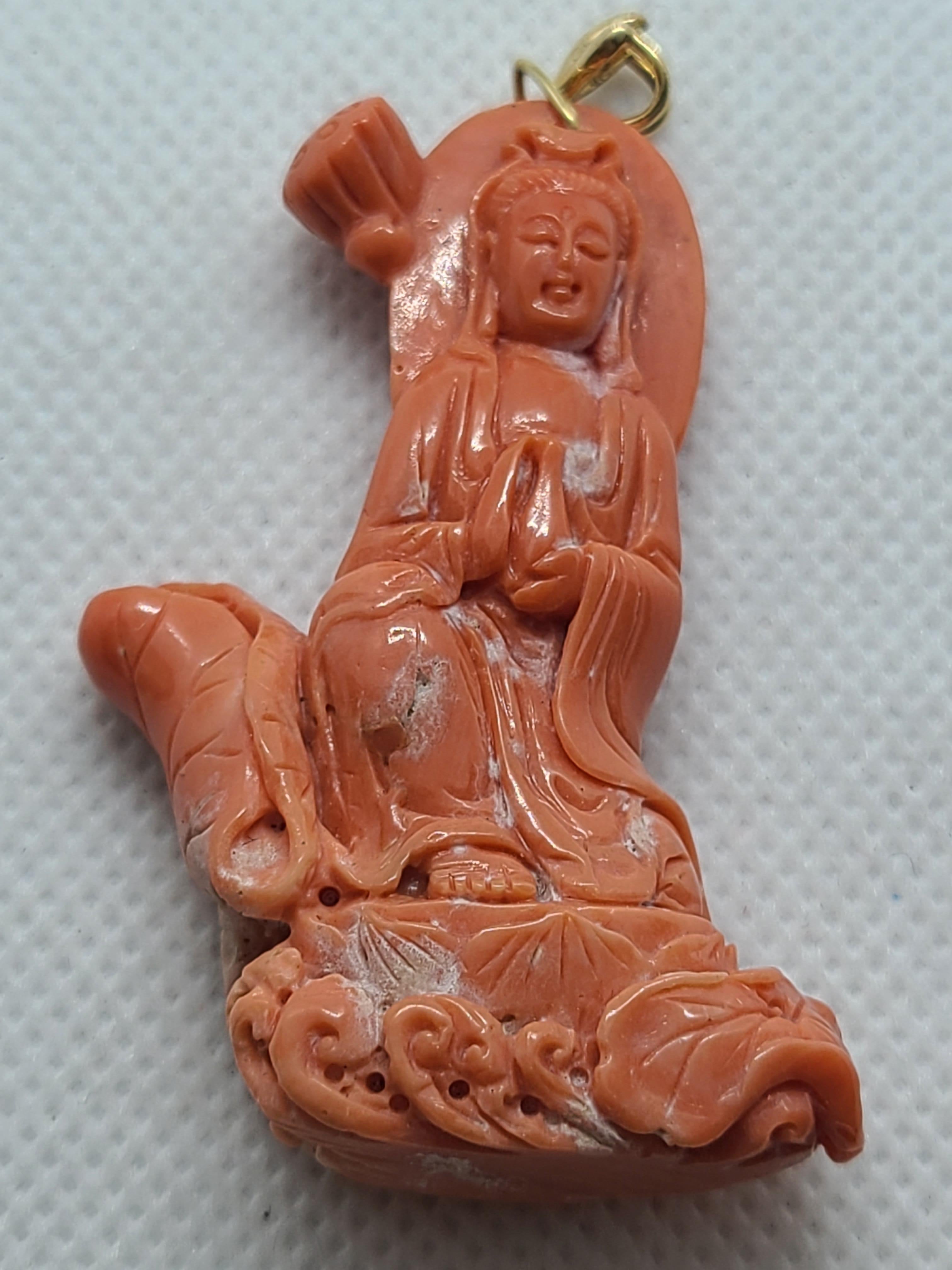 Ce pendentif est composé de corail rouge orangé naturel, sculpté de manière complexe à l'image de Guanyin, la déesse de la compassion. Guanyin est représentée tenant une bouteille de paix et assise sur un trône de lotus au milieu de nuages