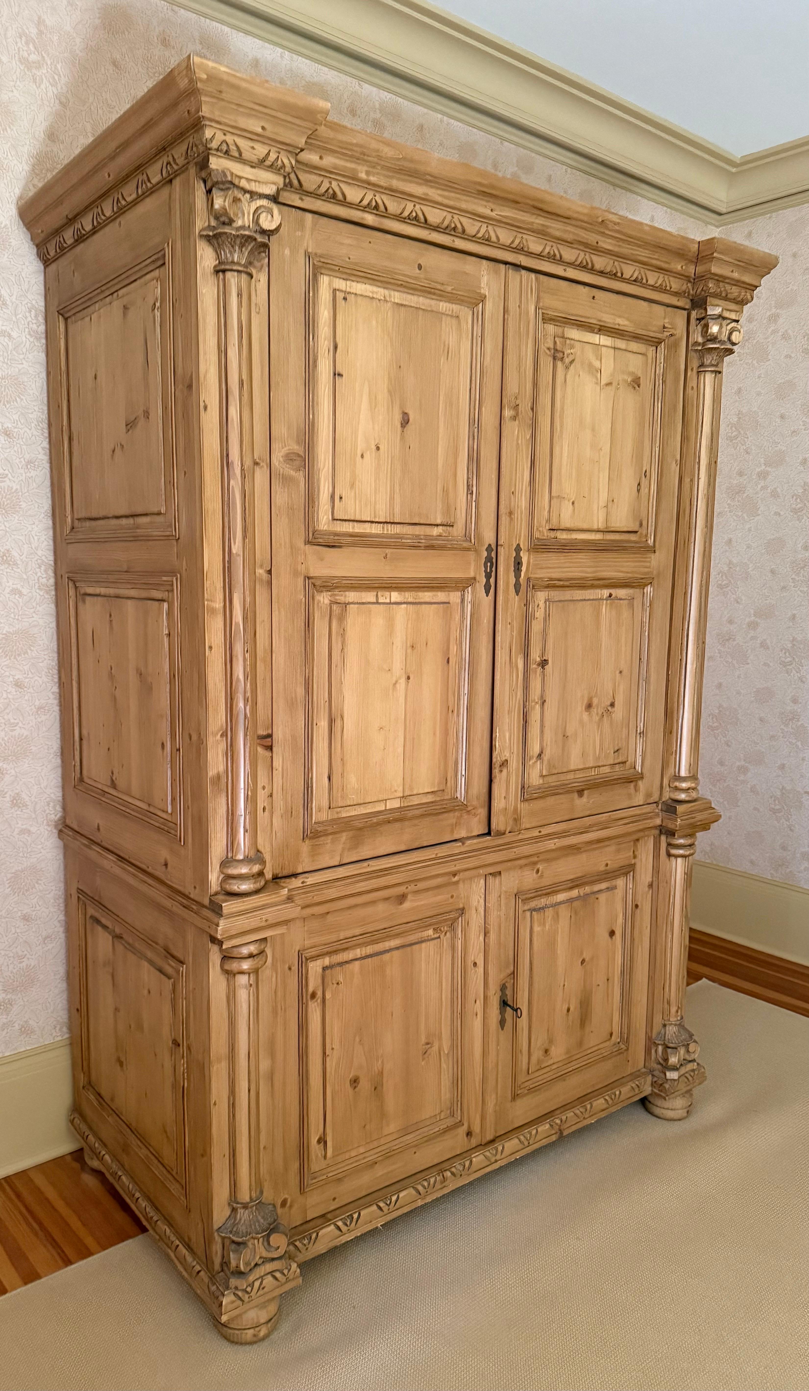 An impressive handcrafted pine linen press armoire, a true testament to New England craftsmanship what with its bold architectural columns, intricate crown molding, and beautiful paneled doors.  Made from solid pine showcasing natural grain and warm