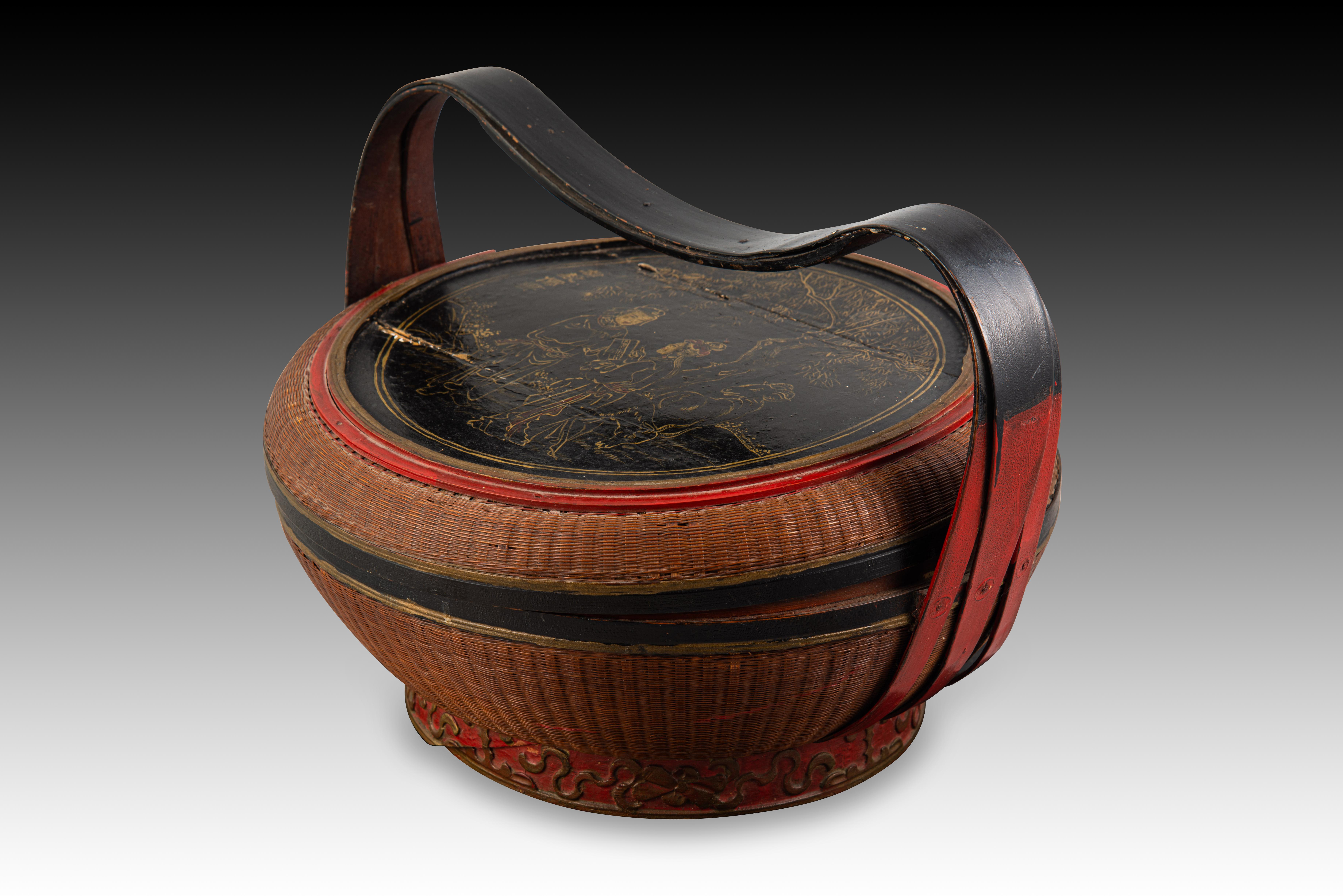 Handcrafted oriental basket. Around 1950. 
Oriental basket with a circular base and shape that has a handle and a Chinese-inspired decoration, an influence that can also be seen in the polychrome based on red, black and gold. The cover has a