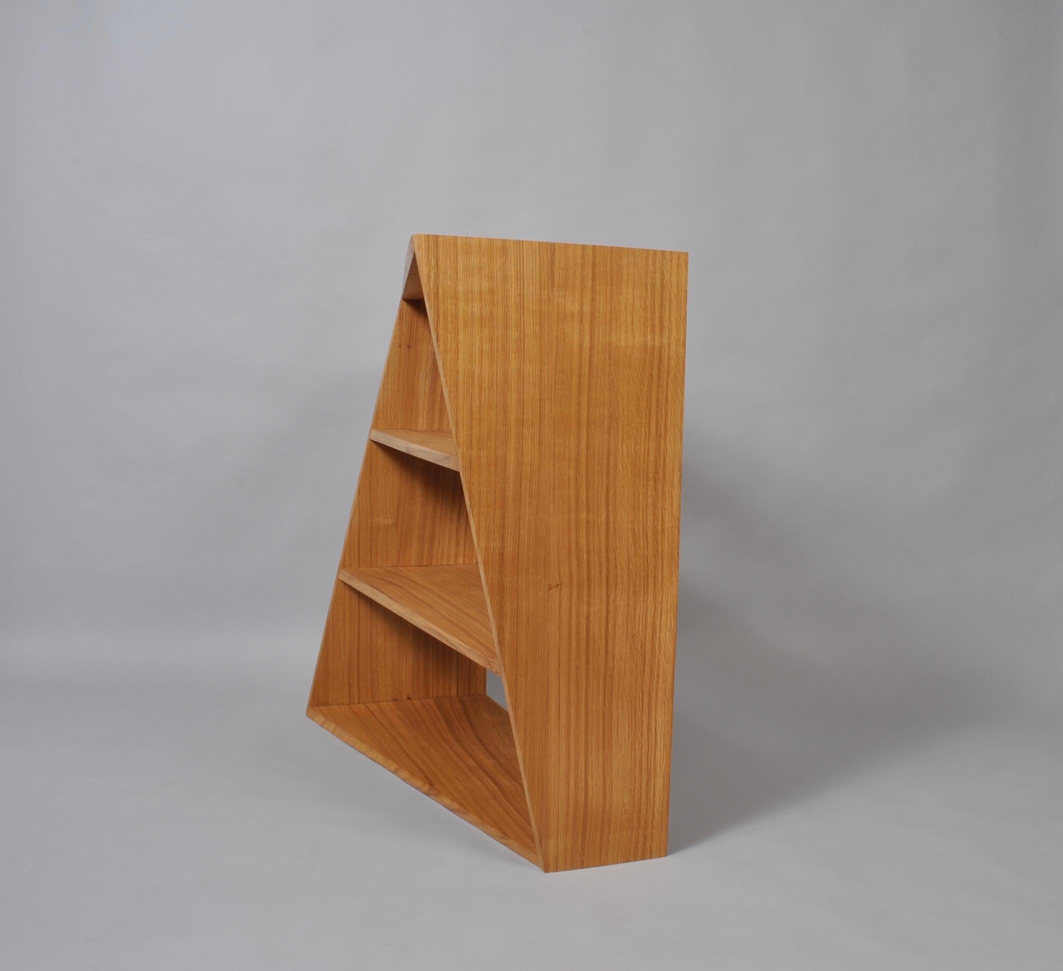 The large Postmodern oak units can be either wall-mounted or freestanding. The acute twisted angle design fools the eye in a similar fashion to the Penrose and Escher staircase. The shelf fronts have a twisting bevelled edge that neatly turns to