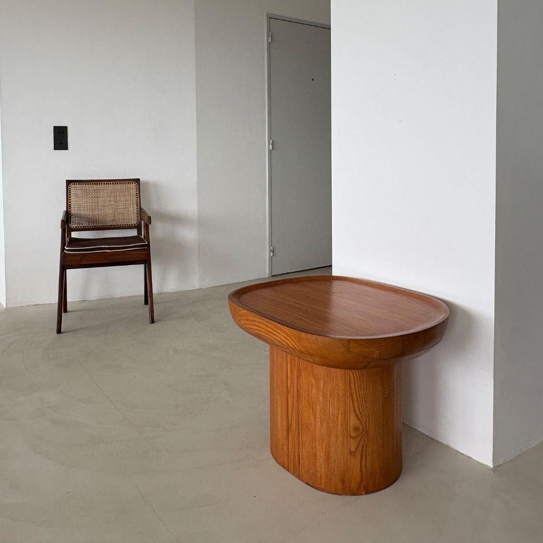 Meticulosamente elaborada a mano con madera maciza de fresno vintage del siglo XX, esta escultural mesa redonda evoca la discreta elegancia del diseño escandinavo de mediados de siglo. Su parte superior ovalada descansa sobre una audaz base