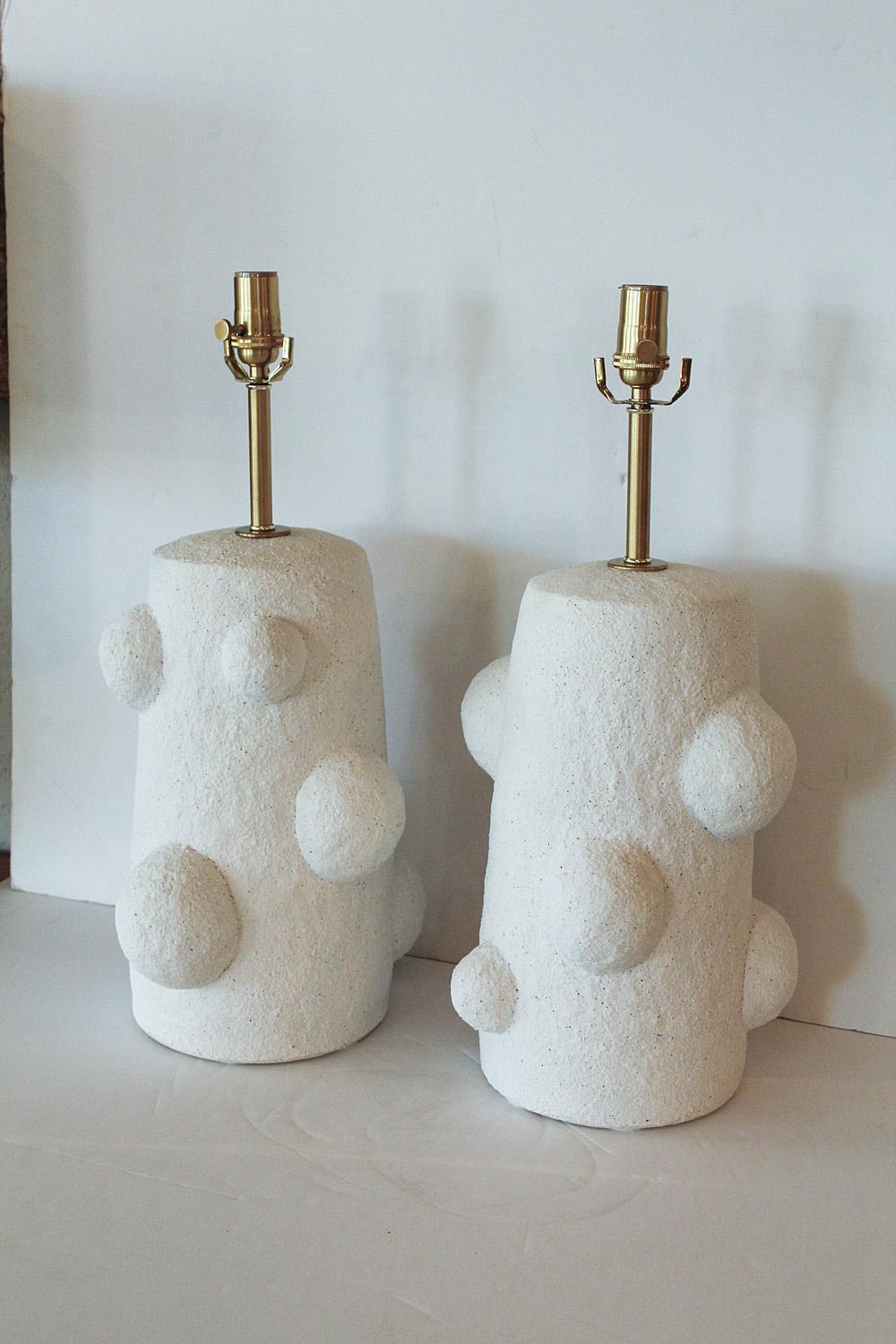 White sand glazed stoneware lamps, handcrafted exclusively for Stripe Vintage Modern by ceramic artist Priscilla Hollingsworth. No molds are used in their manufacture - each pair is entirely hand-built and unique. Solid brass hardware with white