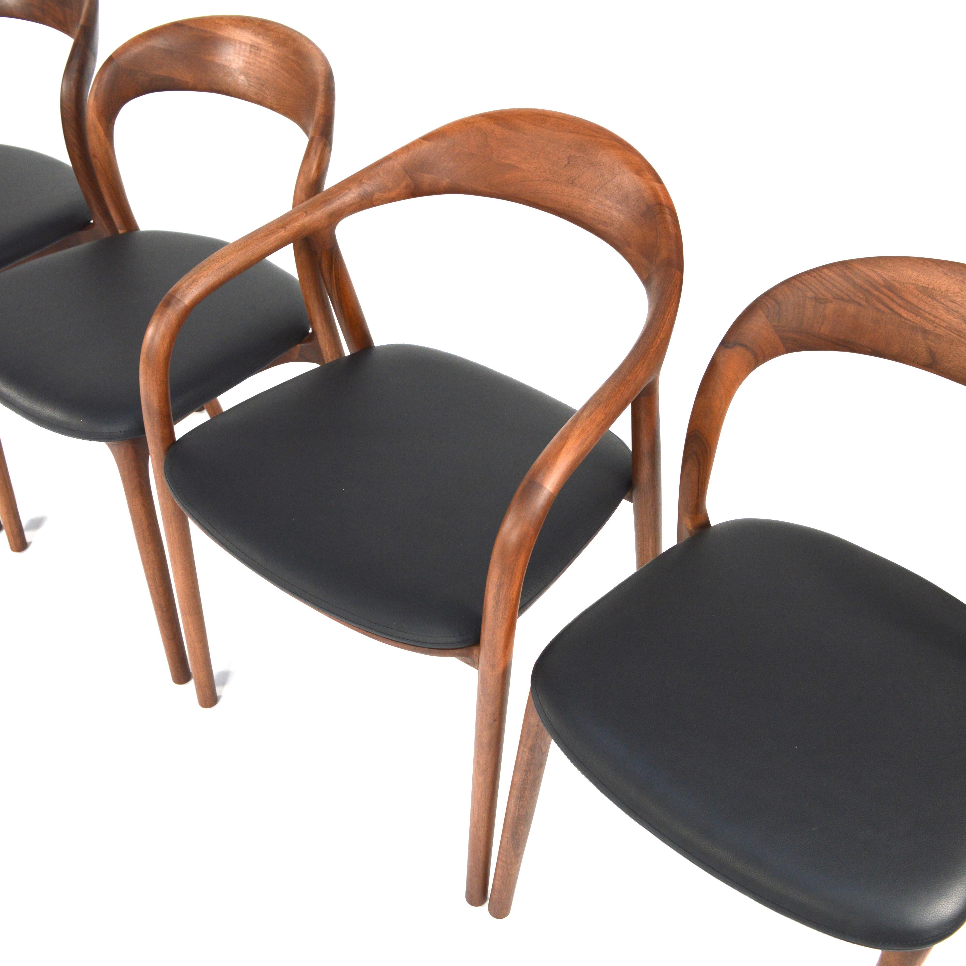 Amazing dining chairs in solid Walnut and black leather. 
These mostly handcrafted chairs in Scandinavian modern style are a real eye catcher and of superior quality.
Included in this listing are two armchairs and four chairs without arms. Different