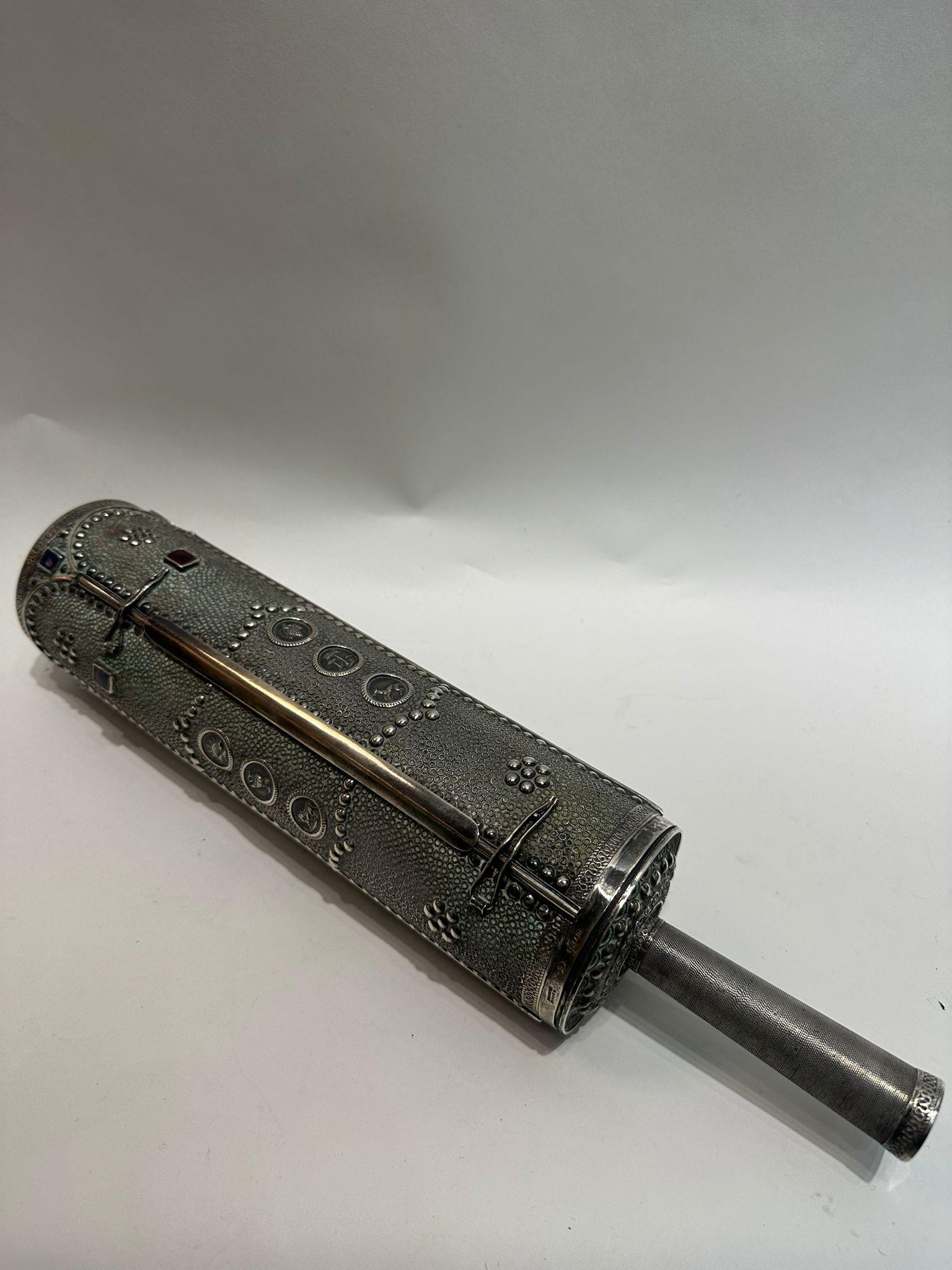 Questa squisita Megillah di Ester (Rotolo di Ester) è racchiusa in un astuccio in argento sterling meticolosamente lavorato a mano, realizzato in Israel nel 1950 dal rinomato argentiere I.M. Fain. La cassa è ornata da un'elaborata lavorazione in