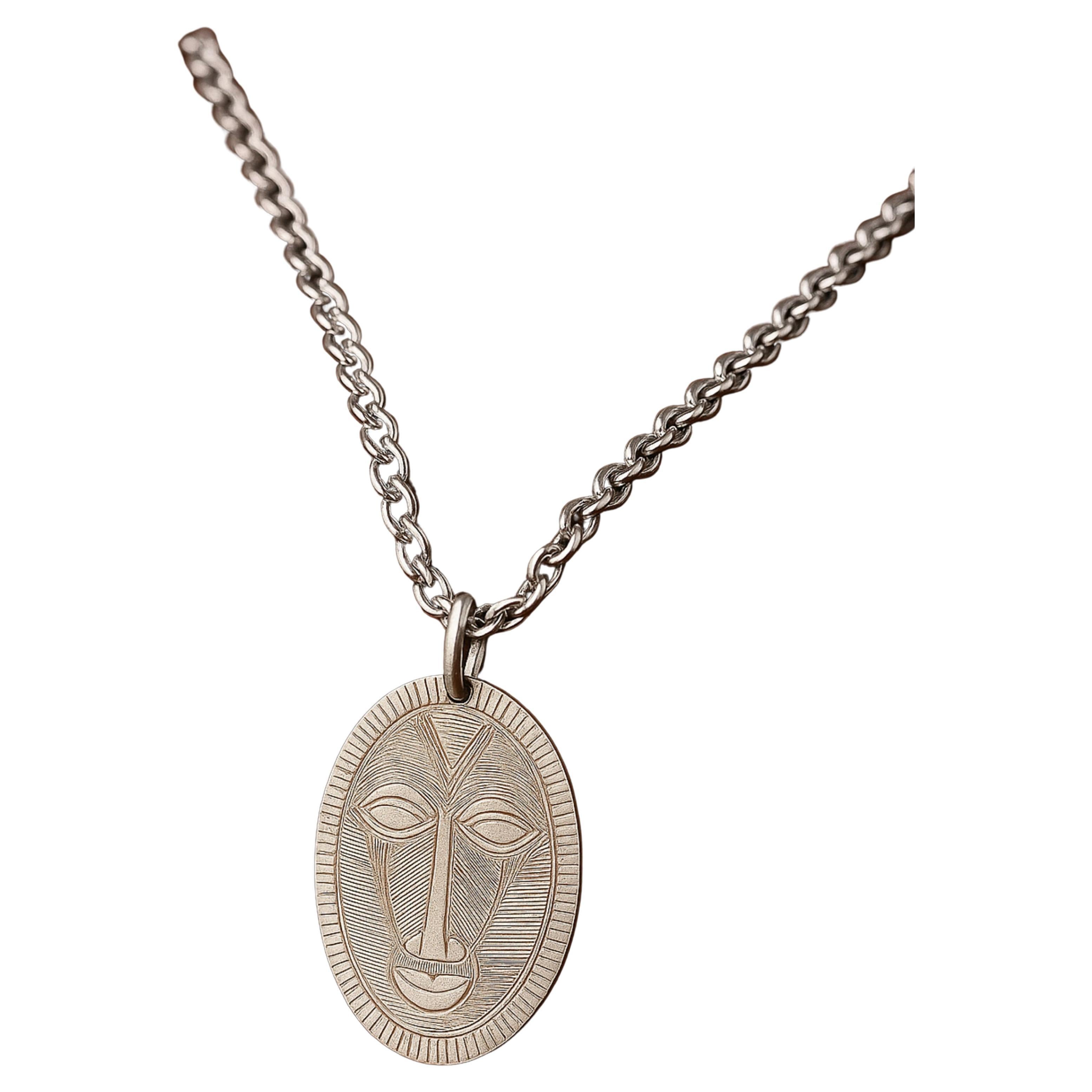 Entdecken Sie unsere exquisite Medaille aus Sterlingsilber (92,5%), die als Hommage an eine traditionelle westafrikanische Maske gefertigt wurde. 

Dieses von einem renommierten Silber- und Goldschmied gefertigte Stück trägt die Silberpunze und