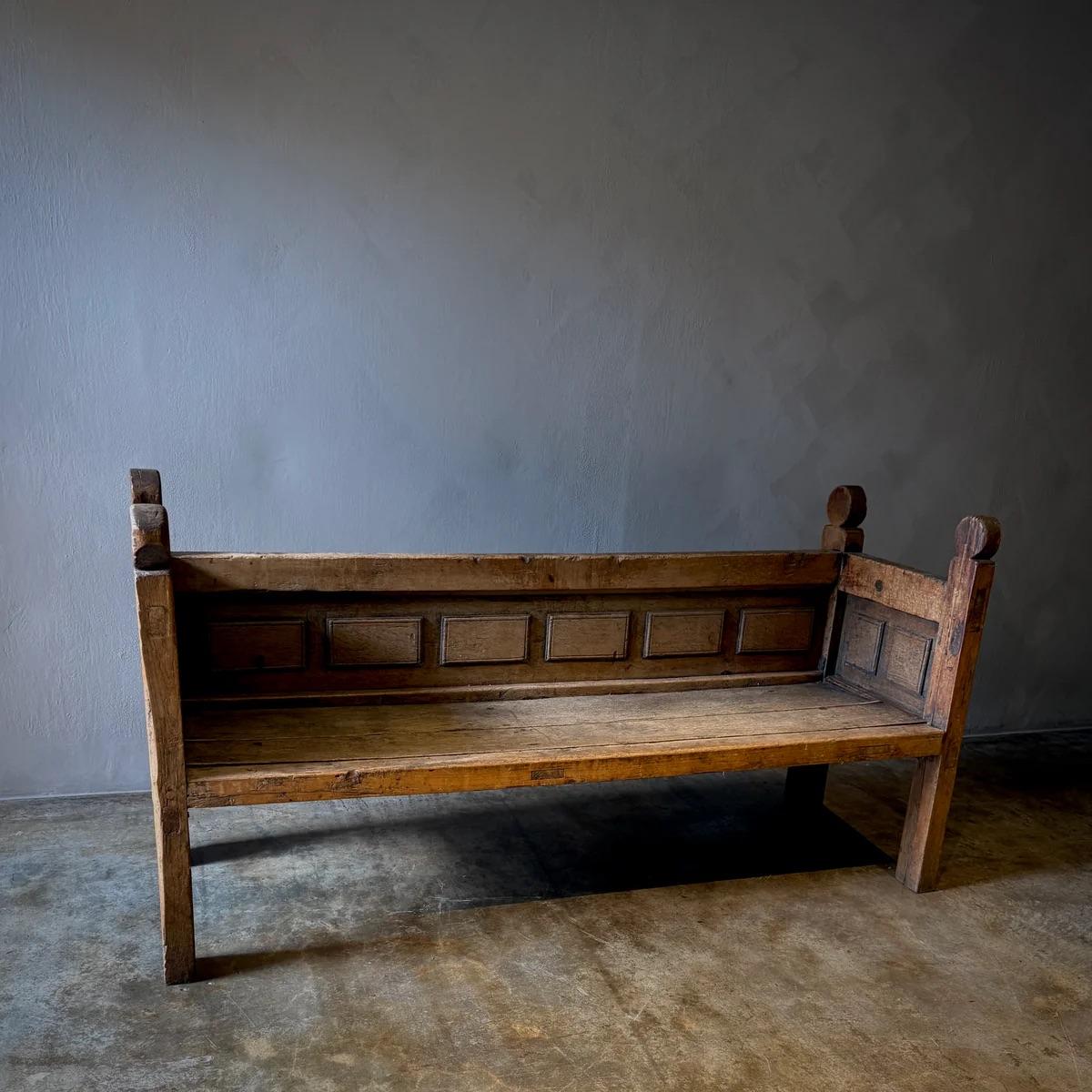 Ce banc espagnol du XIXe siècle témoigne d'un savoir-faire magistral grâce à sa construction en bois massif et à son dossier à panneaux. La riche patine, obtenue après des années d'utilisation, met en valeur la profondeur et la chaleur du bois,