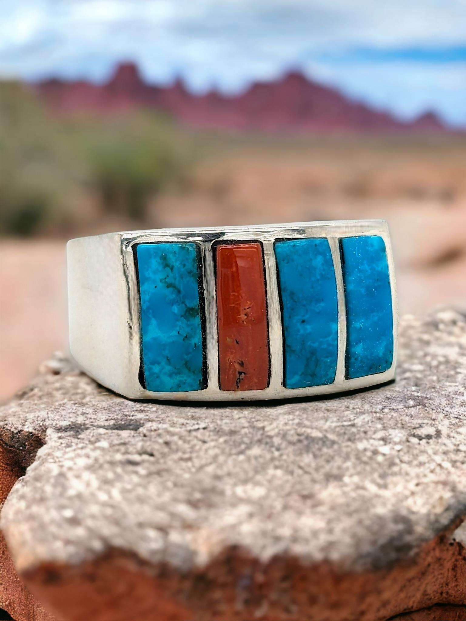 This handcrafted sterling silver ring features a captivating three-stone design symbolizing past, present, and future. Genuine turquoise takes center stage, flanked by fiery red coral gemstones, a classic combination in Southwestern