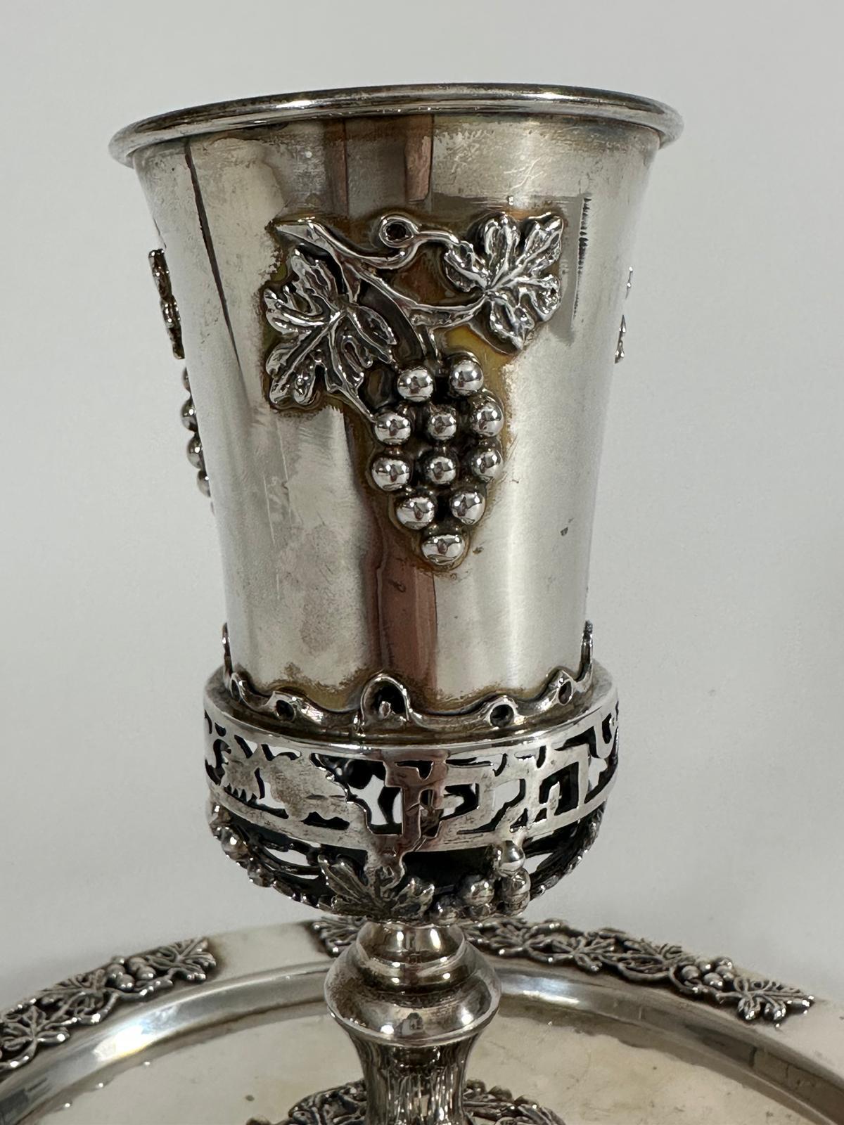 A stunning example of handcrafted Judaica, this sterling silver Kiddush cup and matching base were made in Israel in 1980 and are both signed by the artisan. Elegantly designed and richly detailed, the set reflects the artistry and symbolic