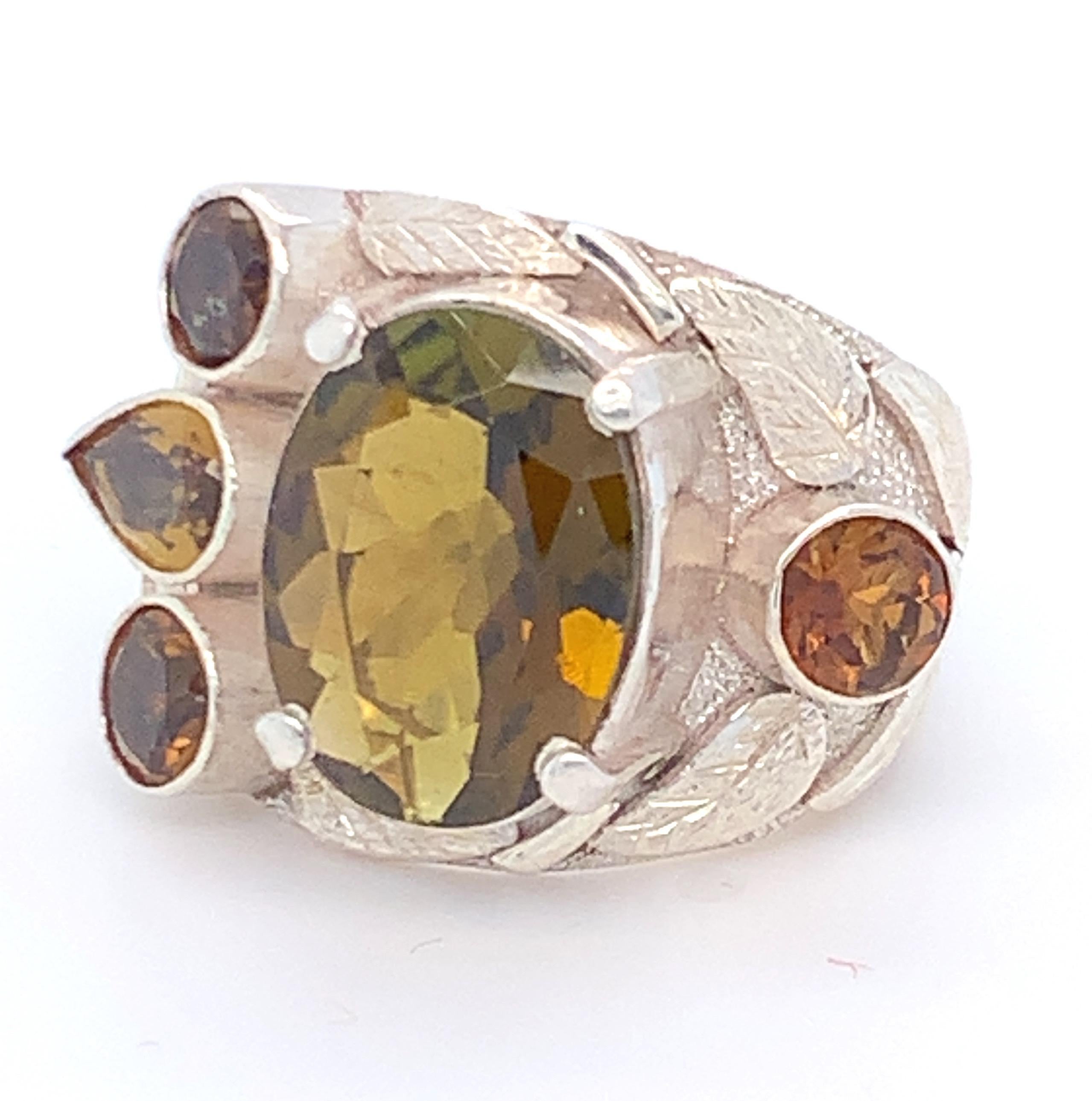 Oval greenish yellow Tourmaline is the main stone with other multi shaped tourmaline are set in asymmetric design. Multi-layer work on the sides enhances the beauty of this ring. Set in sterling silver and carefully crafted with hand makes it a one