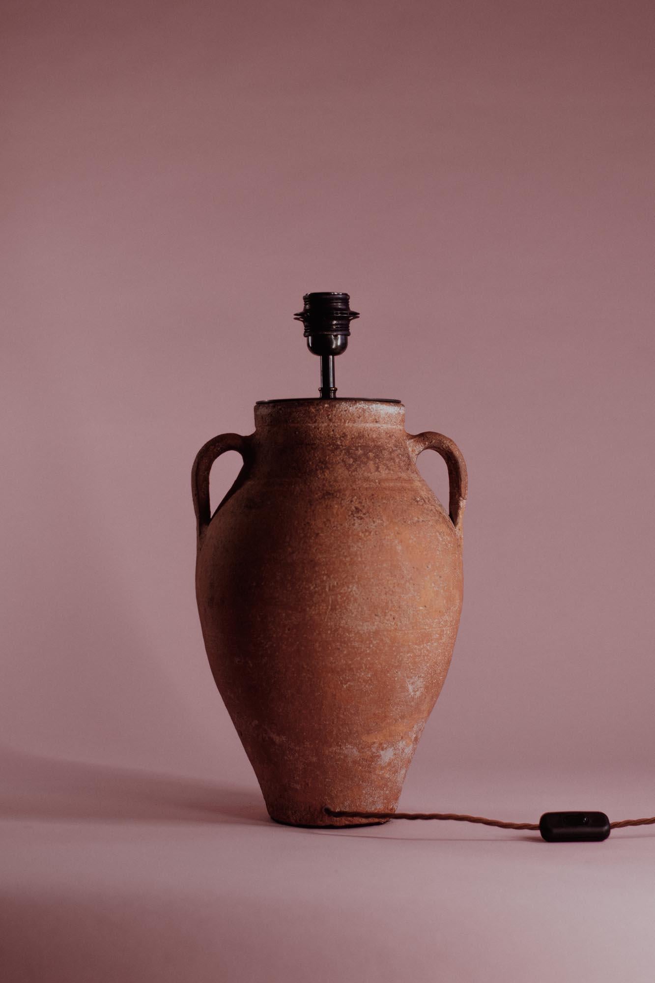 This handcrafted Turkish terracotta table lamp, dating to the 20th century, was originally made using traditional Anatolian pottery techniques. The lamp retains its authentic, practical design, featuring a rounded body with twin handles and a warm