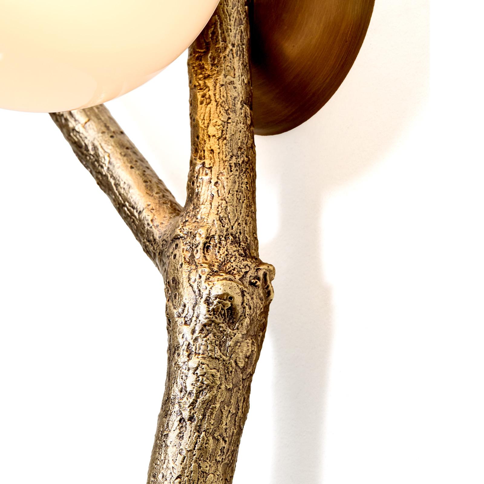 Este aplique encarna la fluidez de la naturaleza, con delicadas ramas que se extienden desde la pared en un abrazo escultural. Cada globo de cristal soplado a mano -disponible en transparente, blanco, bronce o ahumado- presenta sutiles variaciones,