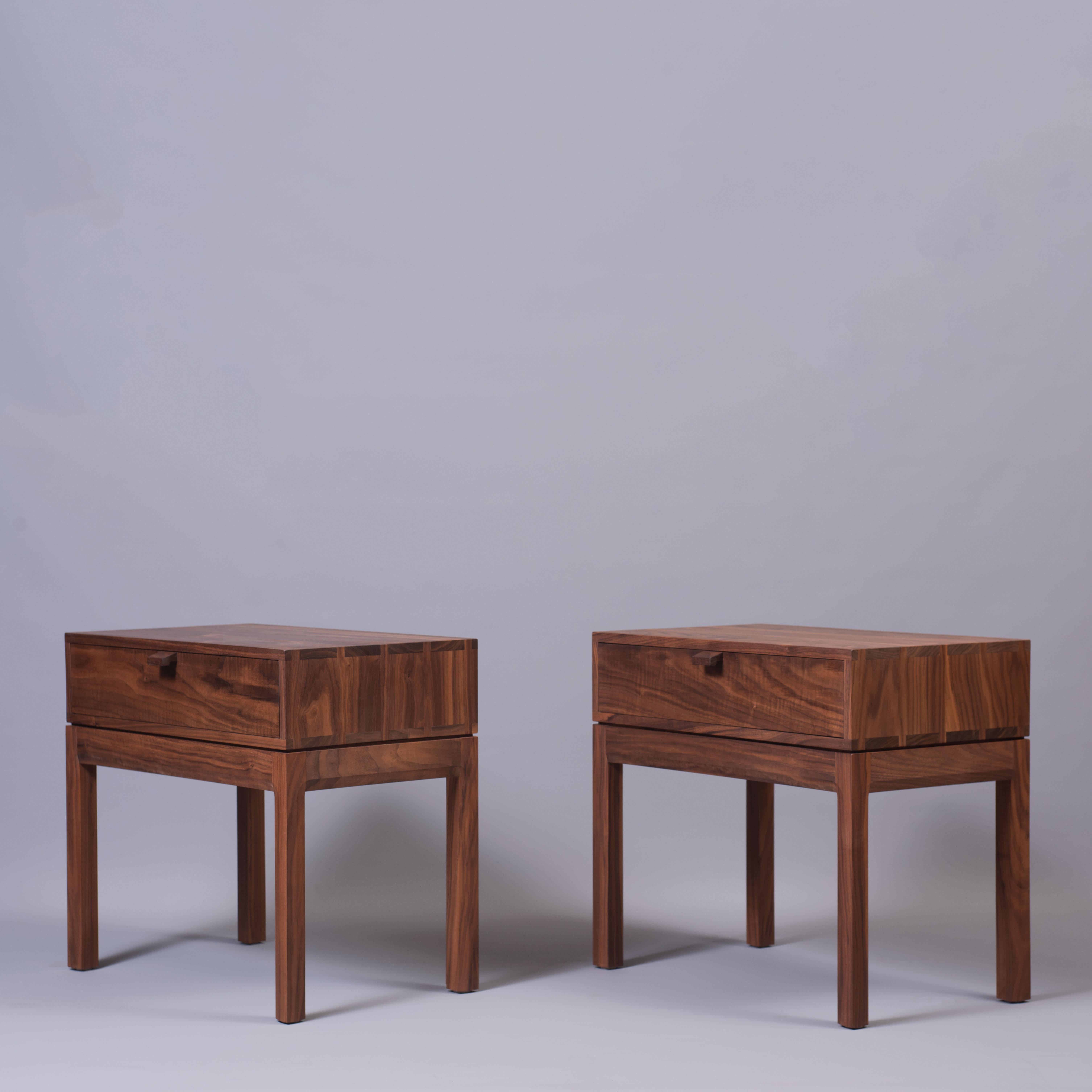 A pair of walnut hand-crafted nightstands in the midcentury style. Constructed from finest American black walnut with the inner dovetailed jointed drawer carcass in English Oak. The upper box is detailed with hand-cut dovetail jointing. A light