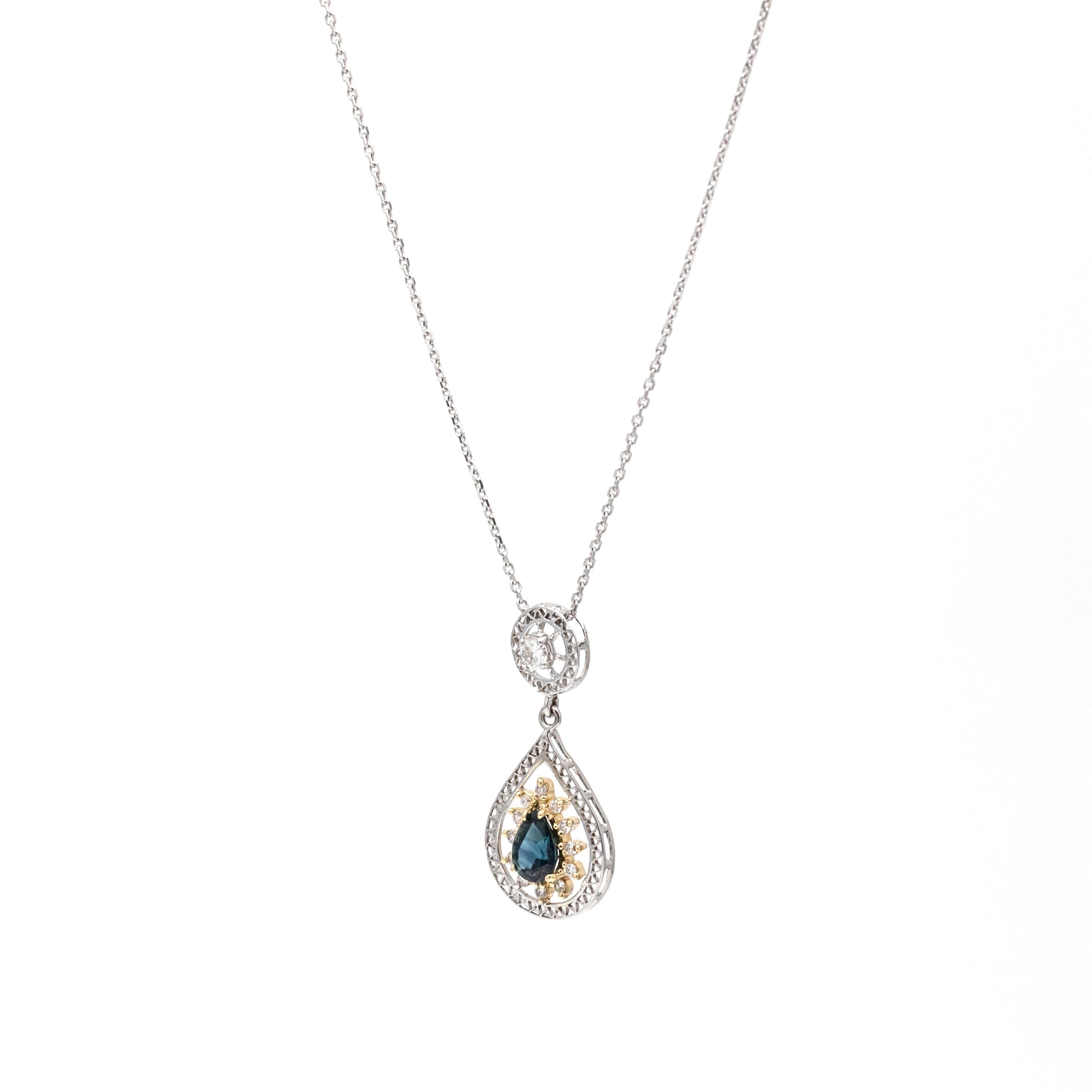 Elevate your jewelry collection with this stunning handmade pendant necklace, exquisitely crafted with delicate openwork. The intricate design showcases a pear-cut natural blue sapphire, surrounded by sparkling round brilliant diamonds and topped