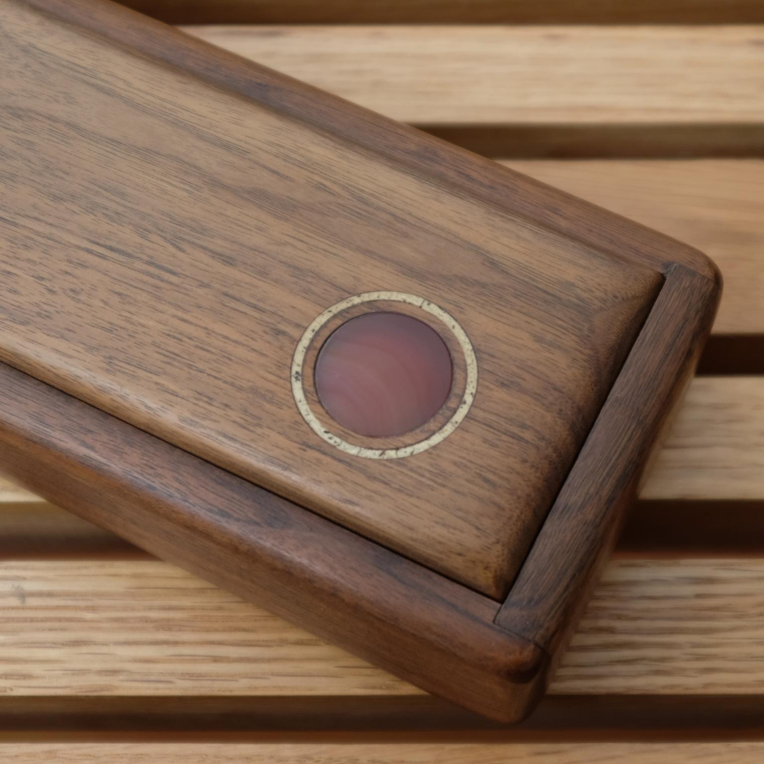 Handcrafted walnut jewelry box with a inlaid wood and carnelian element. The sliding top reveals a maroon velvet lining. The wood divider is removable. 1960s