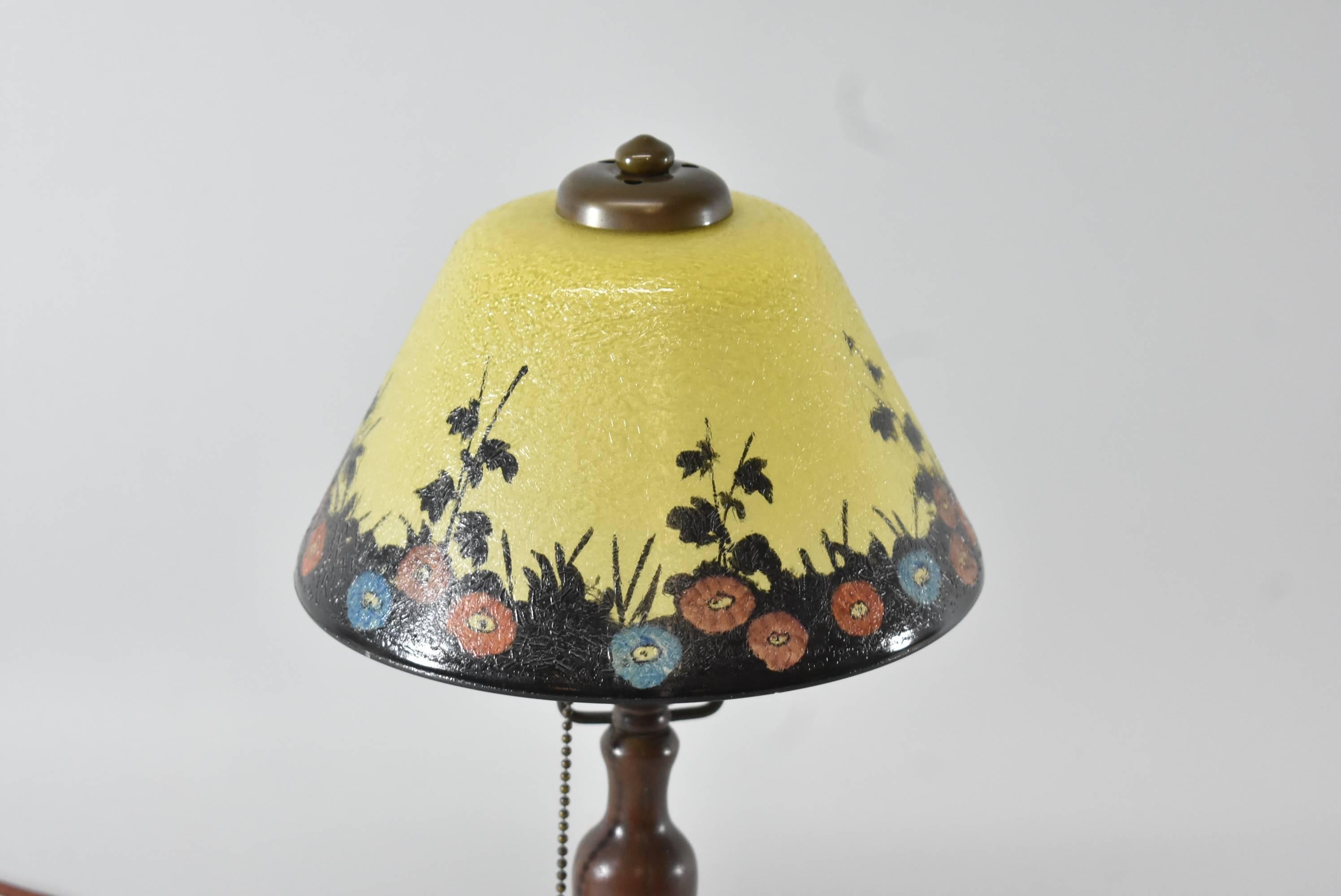 A beautiful Handel reverse painted boudoir lamp. This lovely lamp features an exterior reverse painted floral scene in shades or yellow with a black border and multi-color poppies. The base has a nice patina. Measure: The lamp is 14