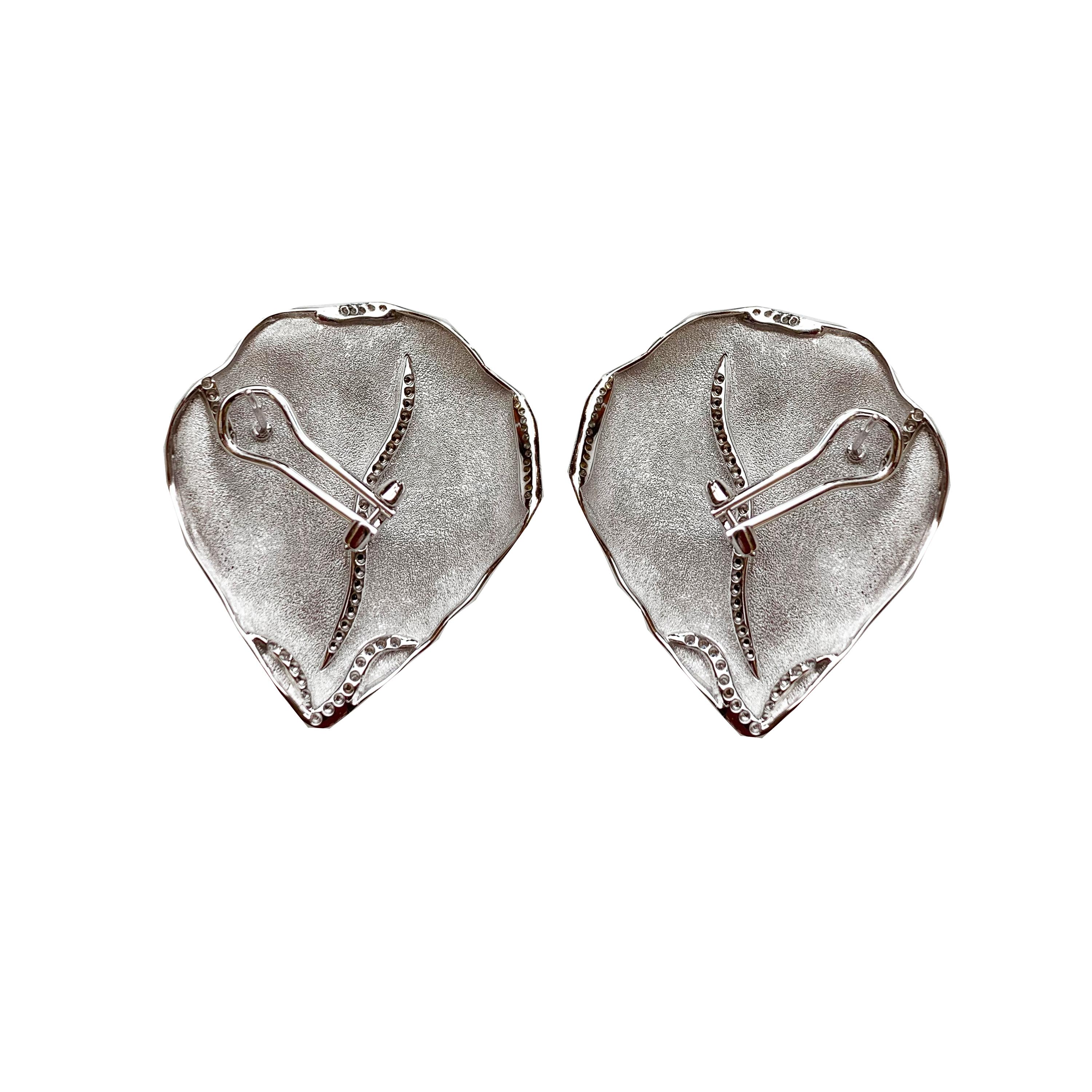 These sophisticated white god earrings have been chiseled  as a petal and the hand engraved giving the gold a shiny silk texture. Rows of white sparkling diamonds have been set to enhance the brightness of these pieces. Completely hand made in Italy