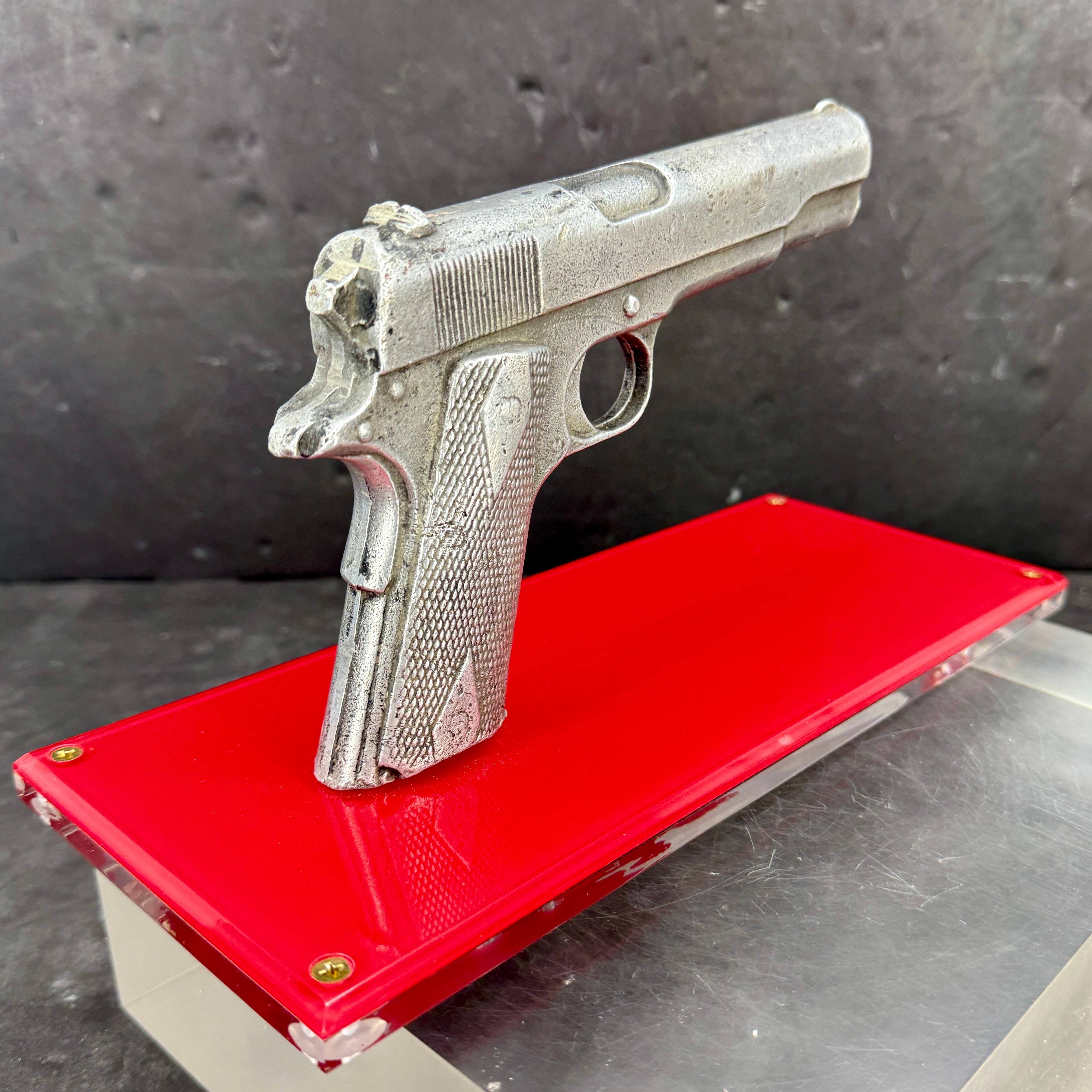 This famous handgun has been created into a one-of-a-kind showpiece. We see this to keep for yourself or give as a gift to an avid collector. Mounted on a lucite stand for display, the piece features a classic statement with modern presentation,