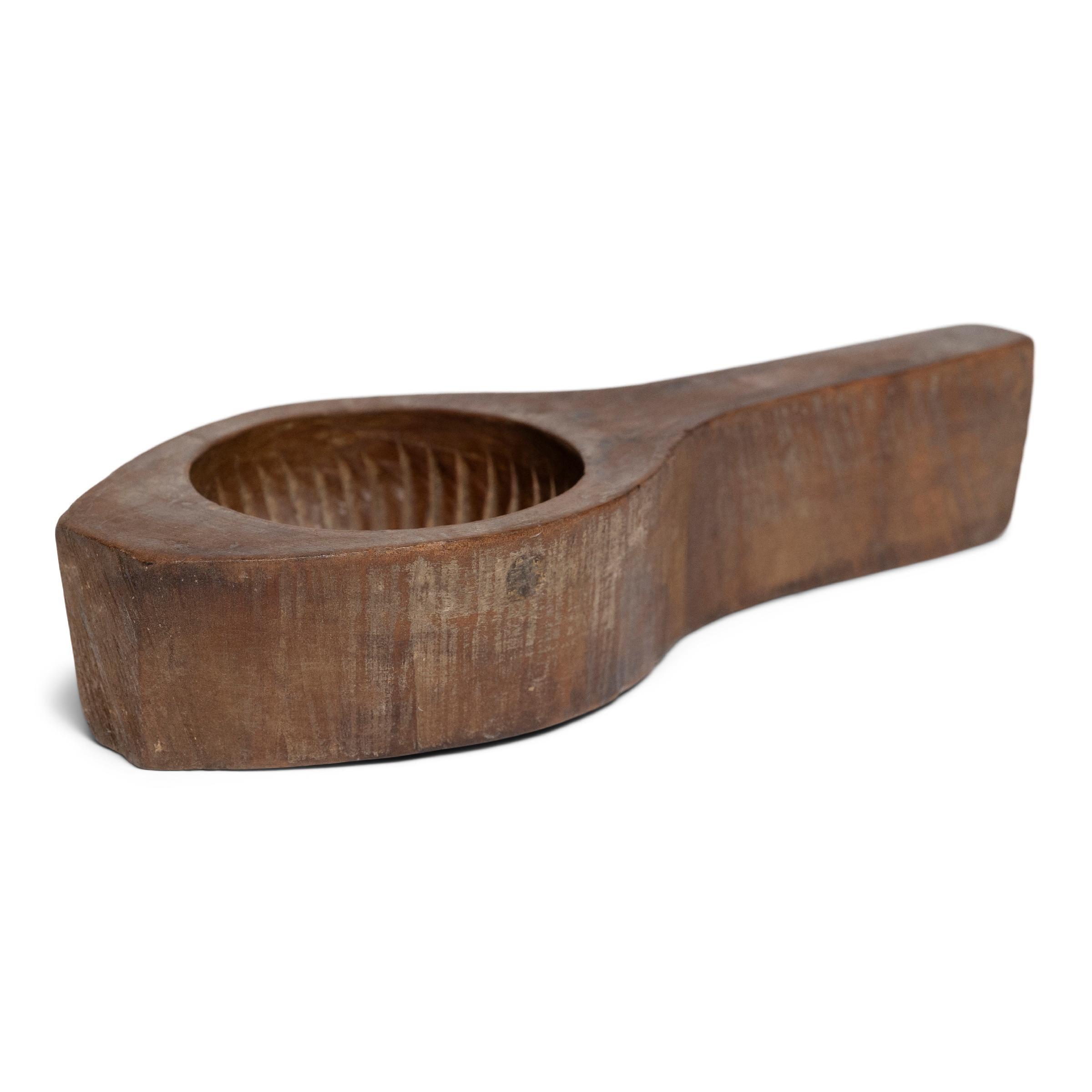 This late 19th century hand-held wood press is carved with a large mold used for shaping festive mooncakes. Packed with lotus root, red bean, or other regional fillings, mooncakes are a delicacy eaten during the Mid-Autumn Festival as an offering
