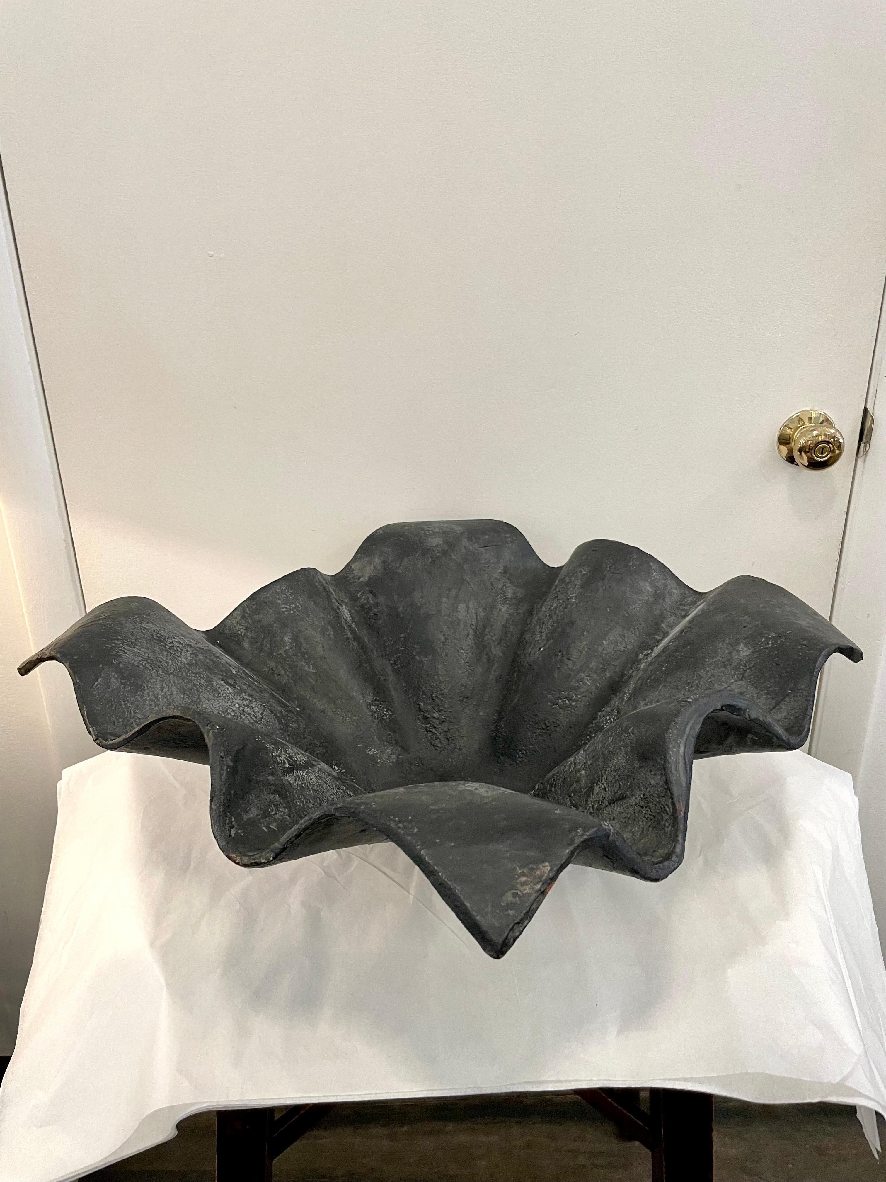 A heavy and oversized iron rough textured centerpiece/ bowl in the shape of a handkerchief in movement.