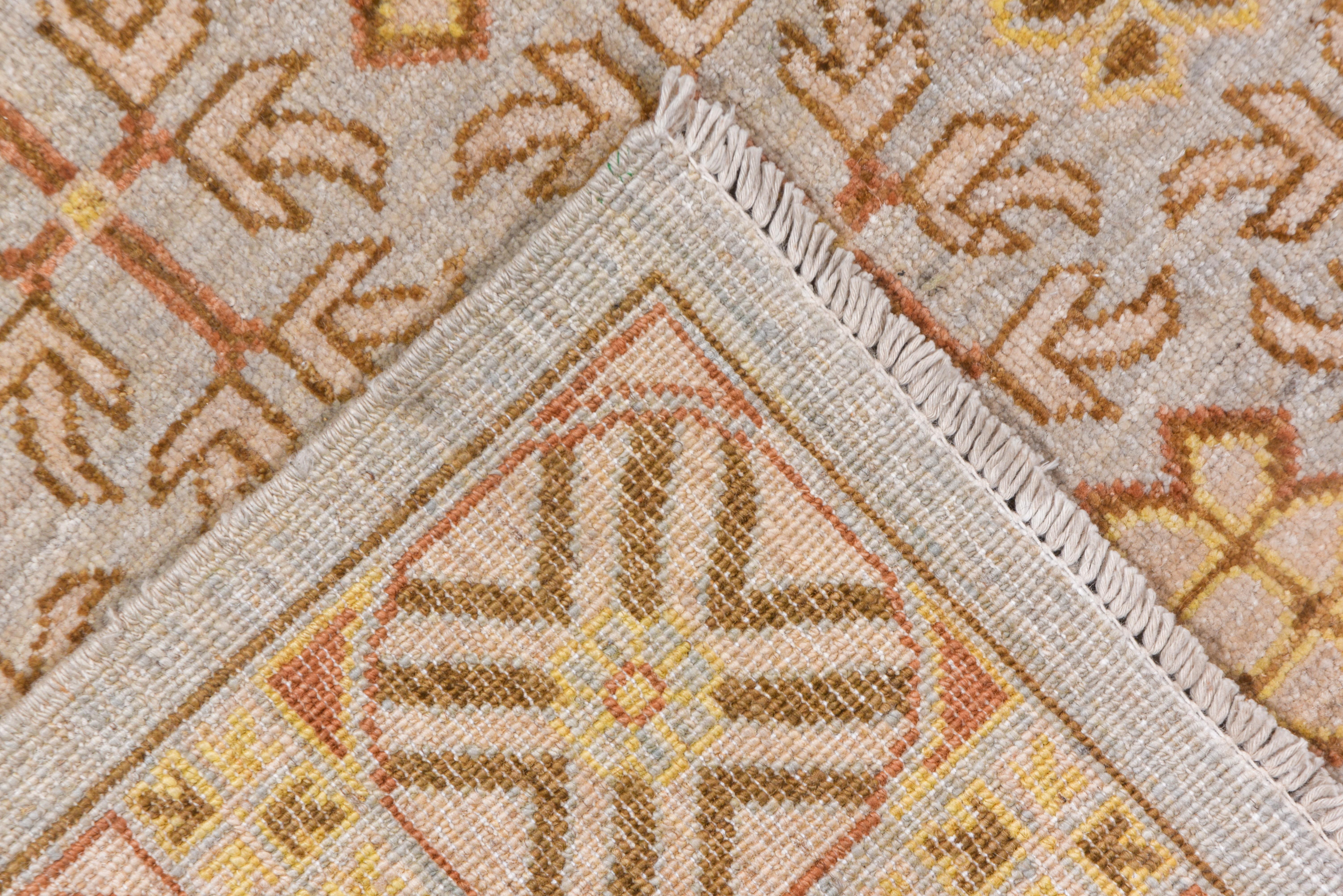 The narrow border of X's within circles frames the close orthogonal repeat of an alternation of four pairs of simple flowers set crosswise and the nine section lappet squares, all on an ivory ground. Copious rust accents.