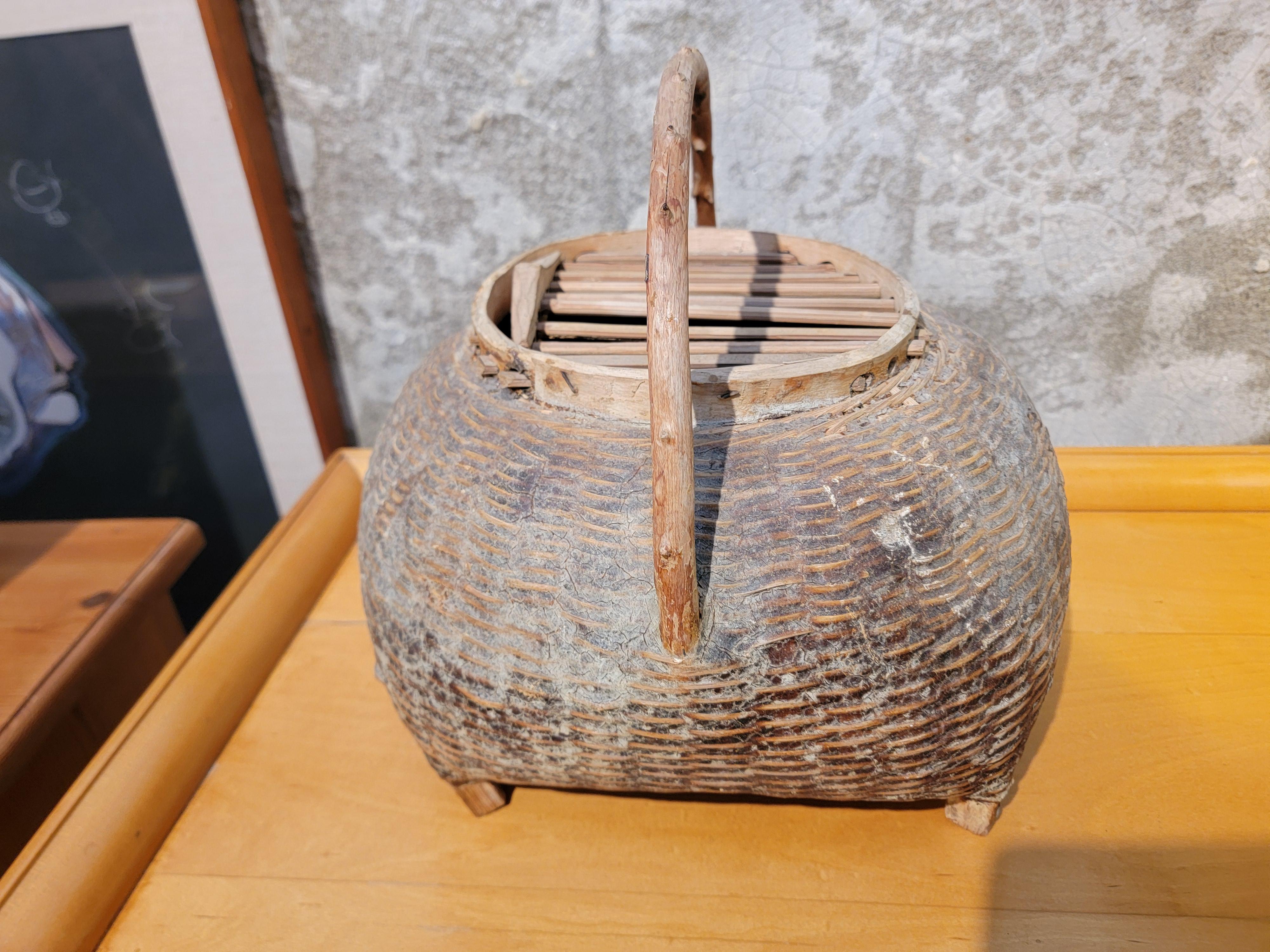 Un cestino vintage intrecciato a mano con una guida scorrevole. Presumibilmente utilizzato per il trasporto di uccelli vivi. Bella patina con manico in Branch.