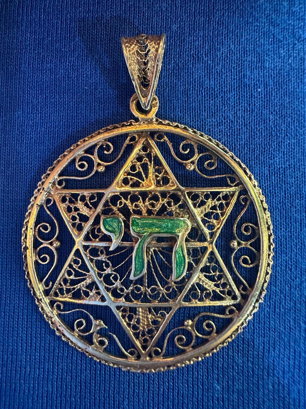 This exquisite handmade 14k gold filigree pendant features a Star of David as its central motif, adorned with intricate openwork filigree that showcases delicate swirling patterns, giving it an elegant and refined appearance.

At the heart of the
