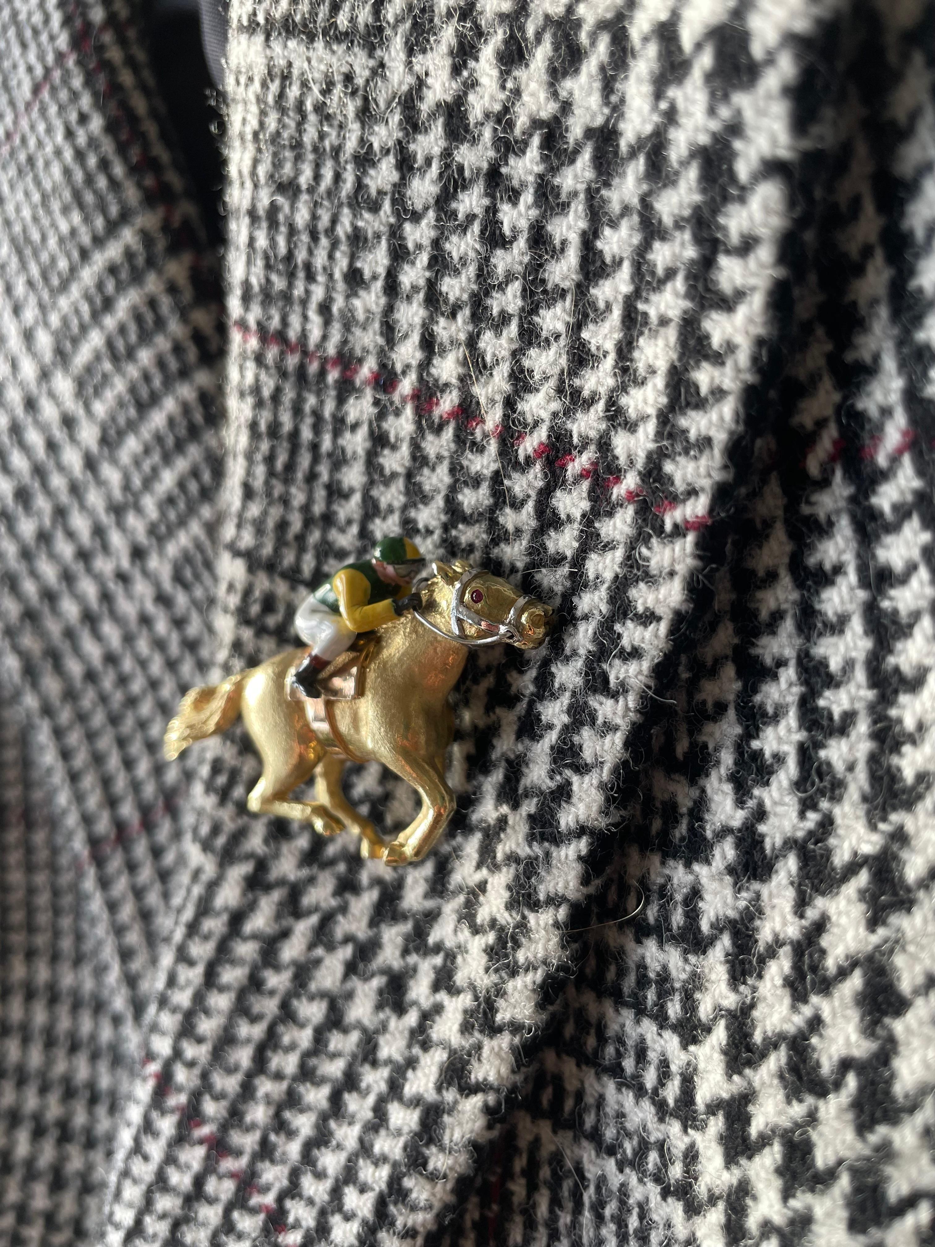 E Wolfe & Company handmade 18 carat yellow gold racehorse brooch. This brooch has been handmade with great attention to detail in our London Workshop. The brooch depicts a gold racehorse with cabochon ruby eye mid-stride being ridden by an enamelled