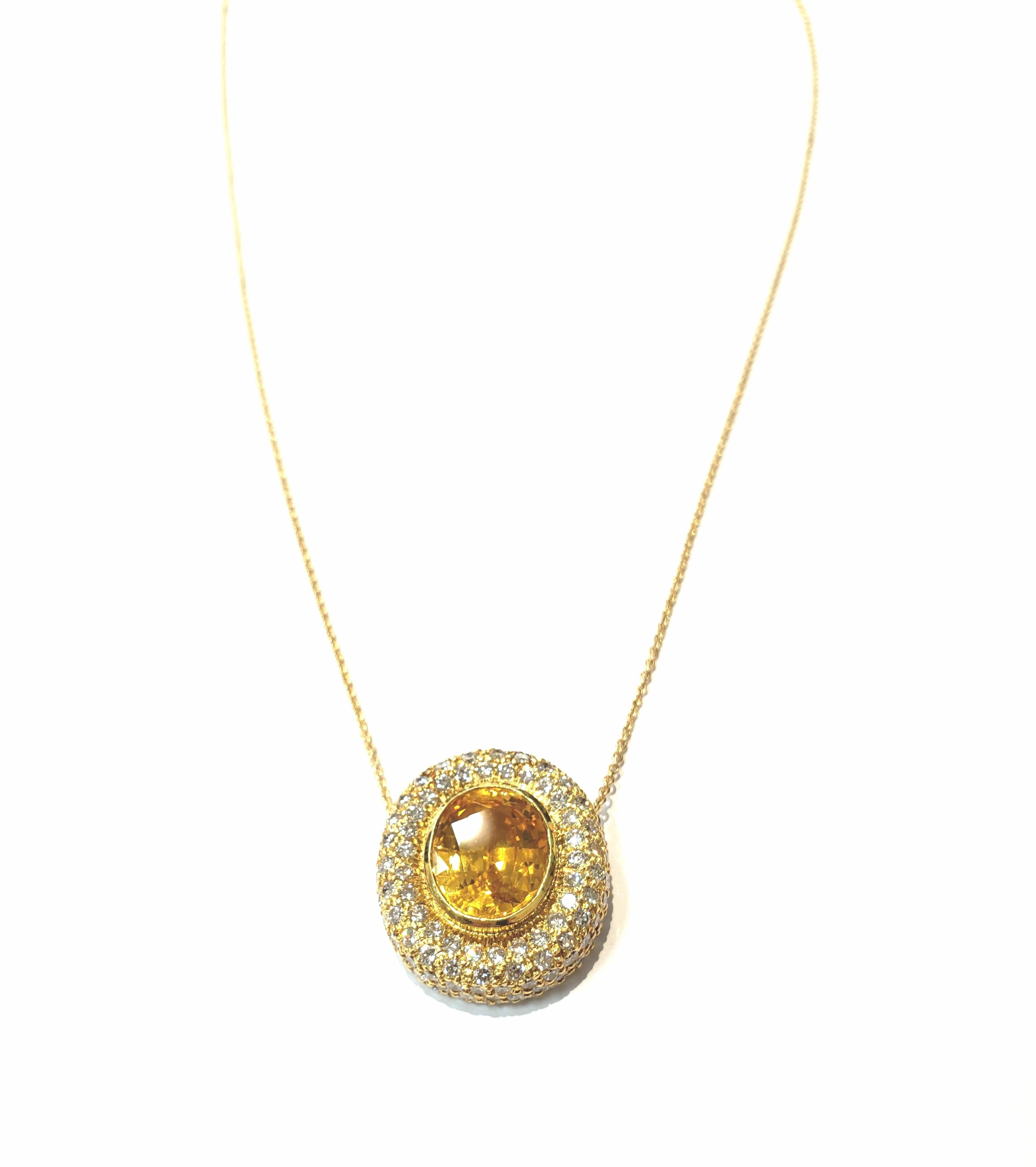 A vivid oval faceted yellow sapphire, bezel set in the center of a handmade 18 karat yellow gold pendant, with
full cut pave set diamonds. Pendant hangs from an 18 inch 1.5 mm yellow gold cable chain.
Oval yellow sapphire is 5.26 carats. It is a