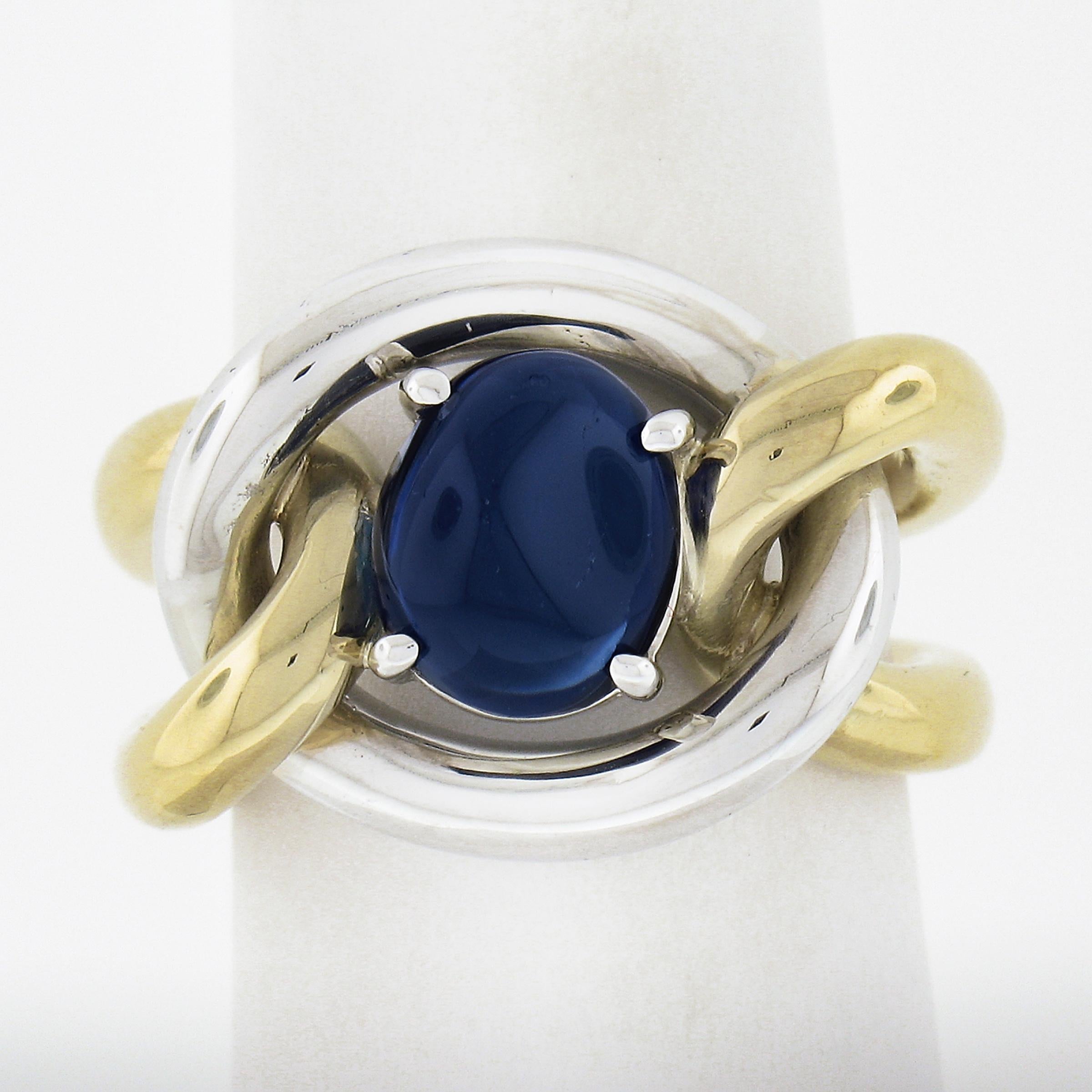 This stunner of a sapphire cocktail ring is very well crafted and handmade in solid 18k gold and features a mesmerizing oval cabochon sapphire solitaire carefully claw-prong set the center of the knot design. The sapphire has been certified by GIA.