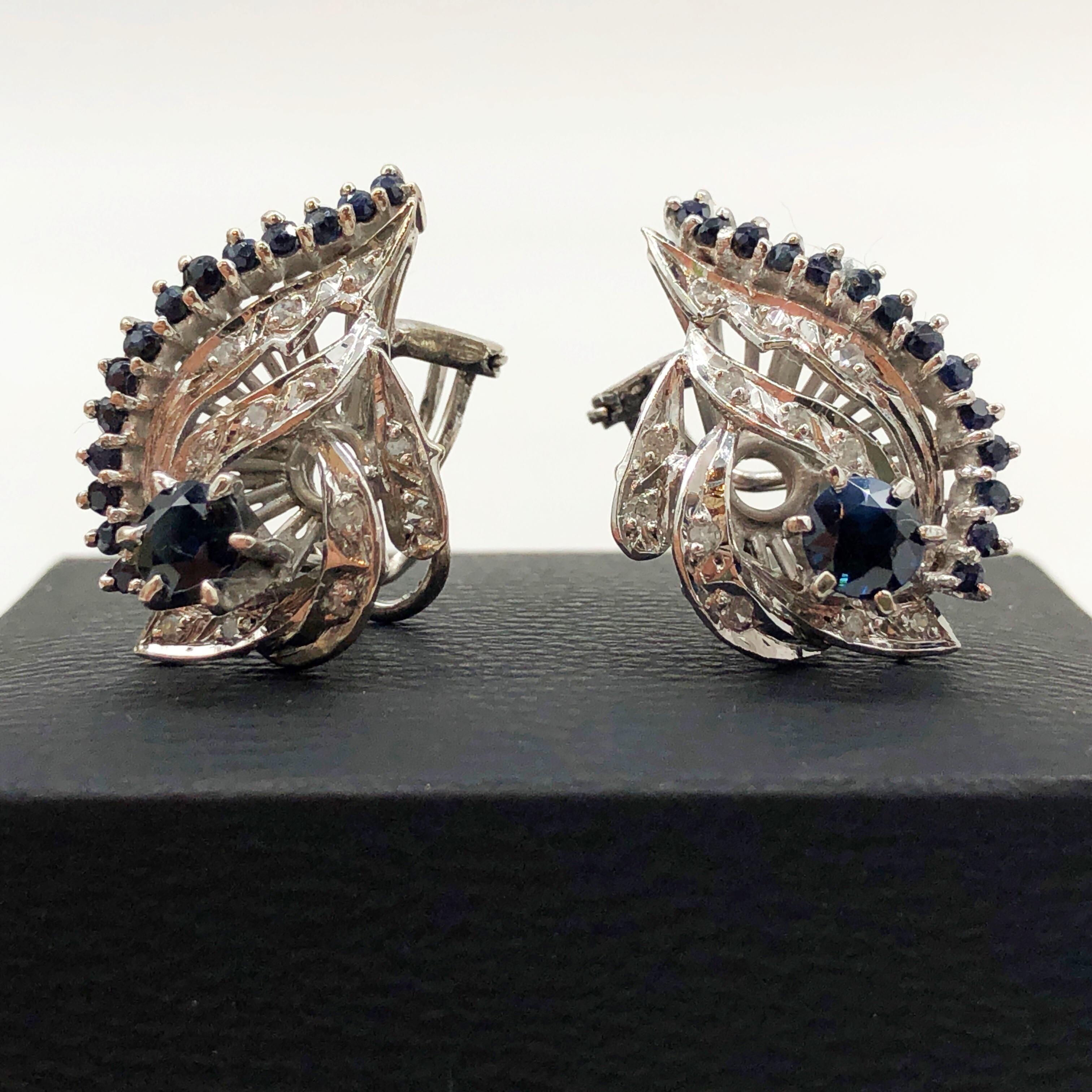 Here is a beautiful and not often seen set of vintage Handmade 1940s PALLADIUM Blue Sapphire and Diamond Cluster Earrings. These earrings each feature a 0.70ct round cut blue sapphire. Center sapphire is heavily included with a dark tone, blue hue,