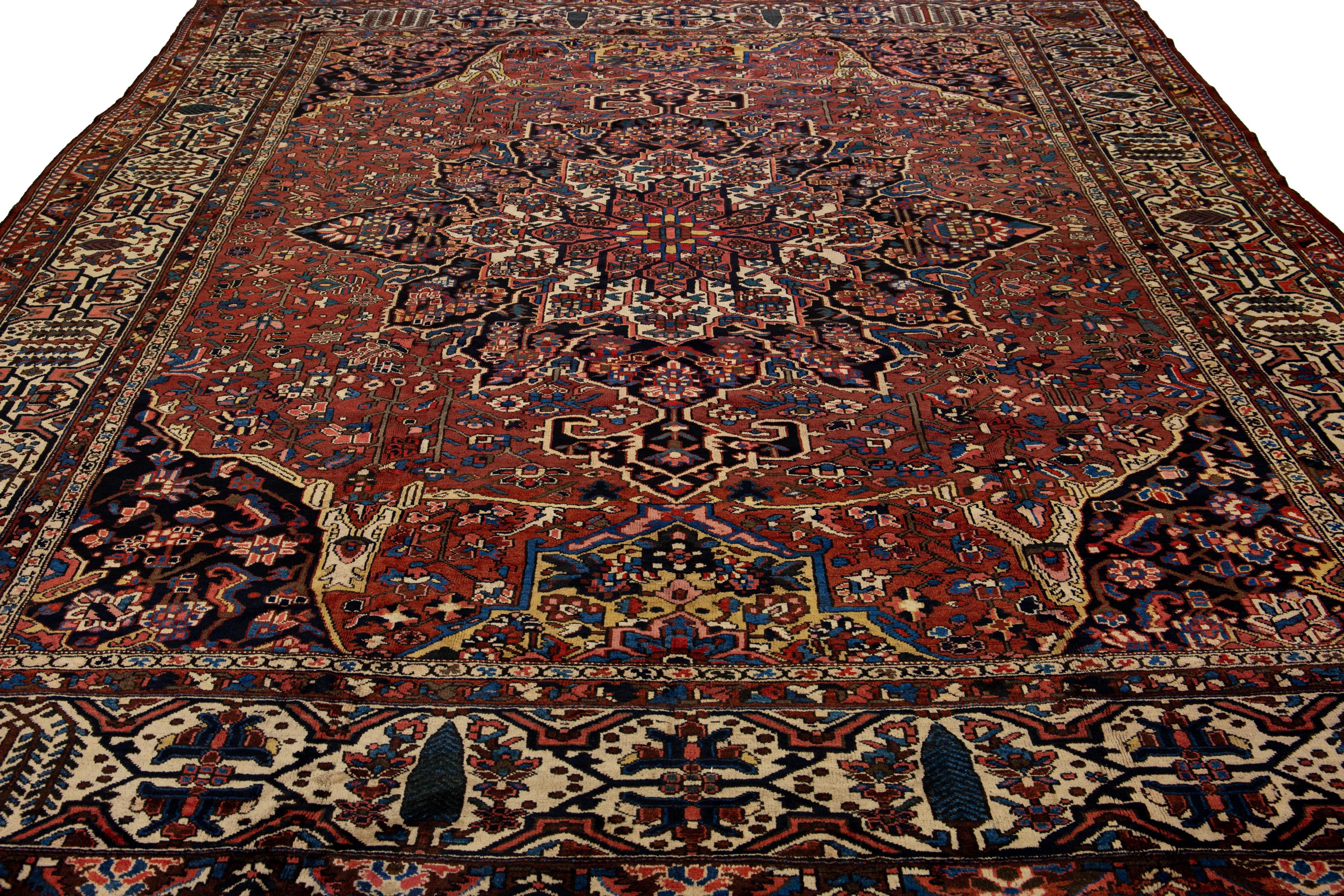 Beautiful Antique Bakhtiari hand-knotted wool rug with a red burgundy field. This Persian piece has an all-over multicolor accent in a gorgeous classic Medallion motif.

This rug measures 12'5