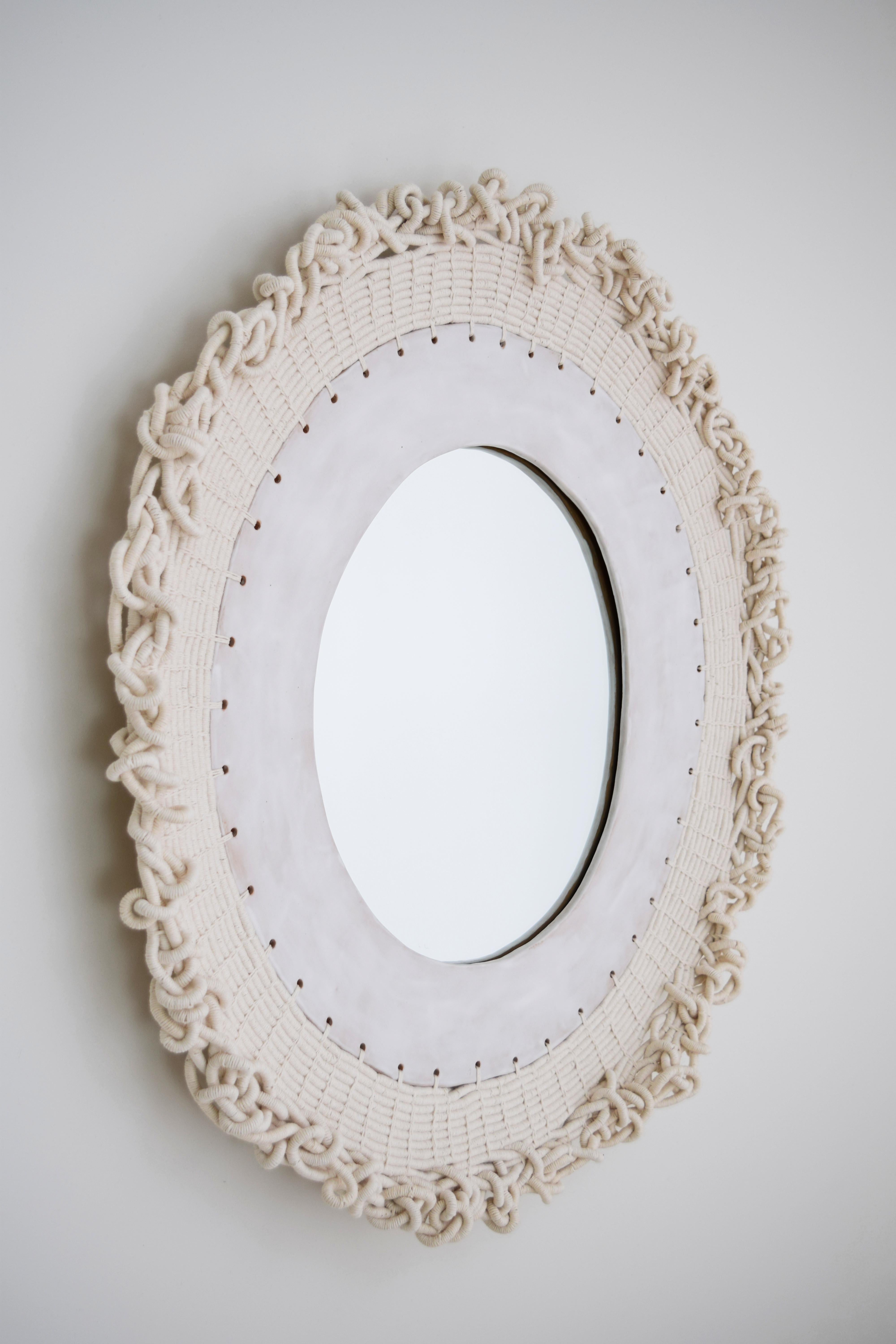 Mirror #773 by Karen Gayle Tinney.

Mirror with a hand formed stoneware frame glazed in satin white. Woven white exterior frame with organic three dimensional shape. Black felt backing on mirror with hanging wire included.

Measures: 30