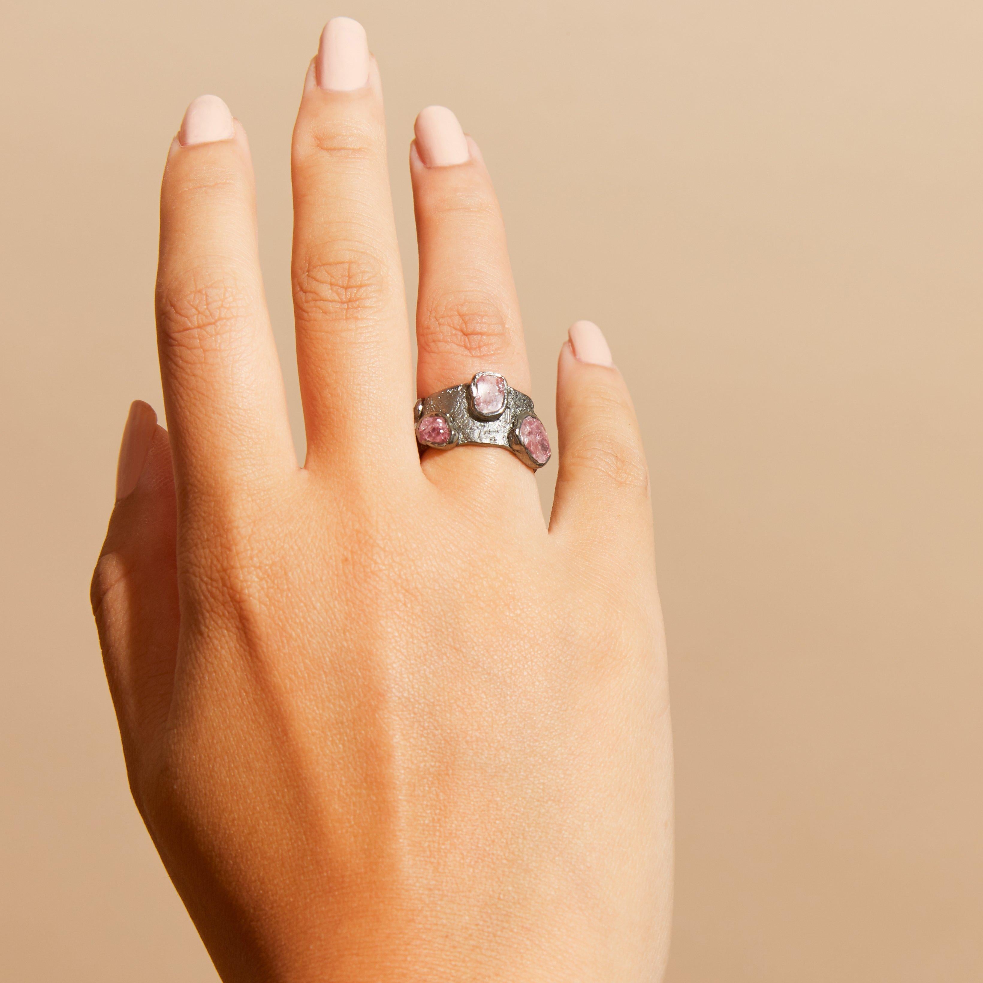 Radiant color glimmers from the depth of the unique gemstone that crowns this ring. A slim band of black anthracite creates the sinuous and curving band and trims of gold grace the edges of the jewel.

