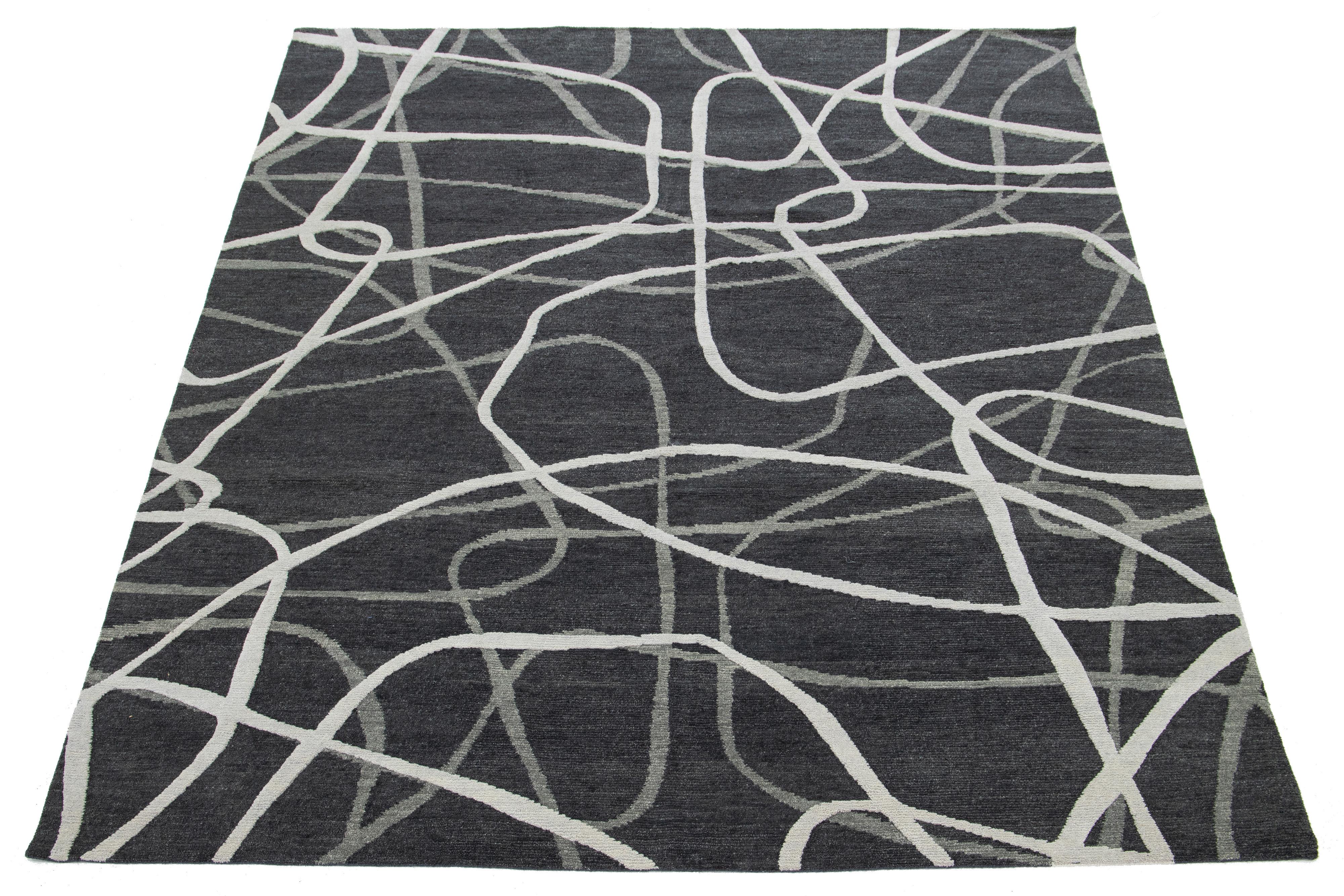 Dieser handgeknüpfte moderne Teppich zeigt ein abstraktes Muster aus dunkelgrauer und elfenbeinfarbener Wolle.

Dieser Teppich misst 8' x 10'.