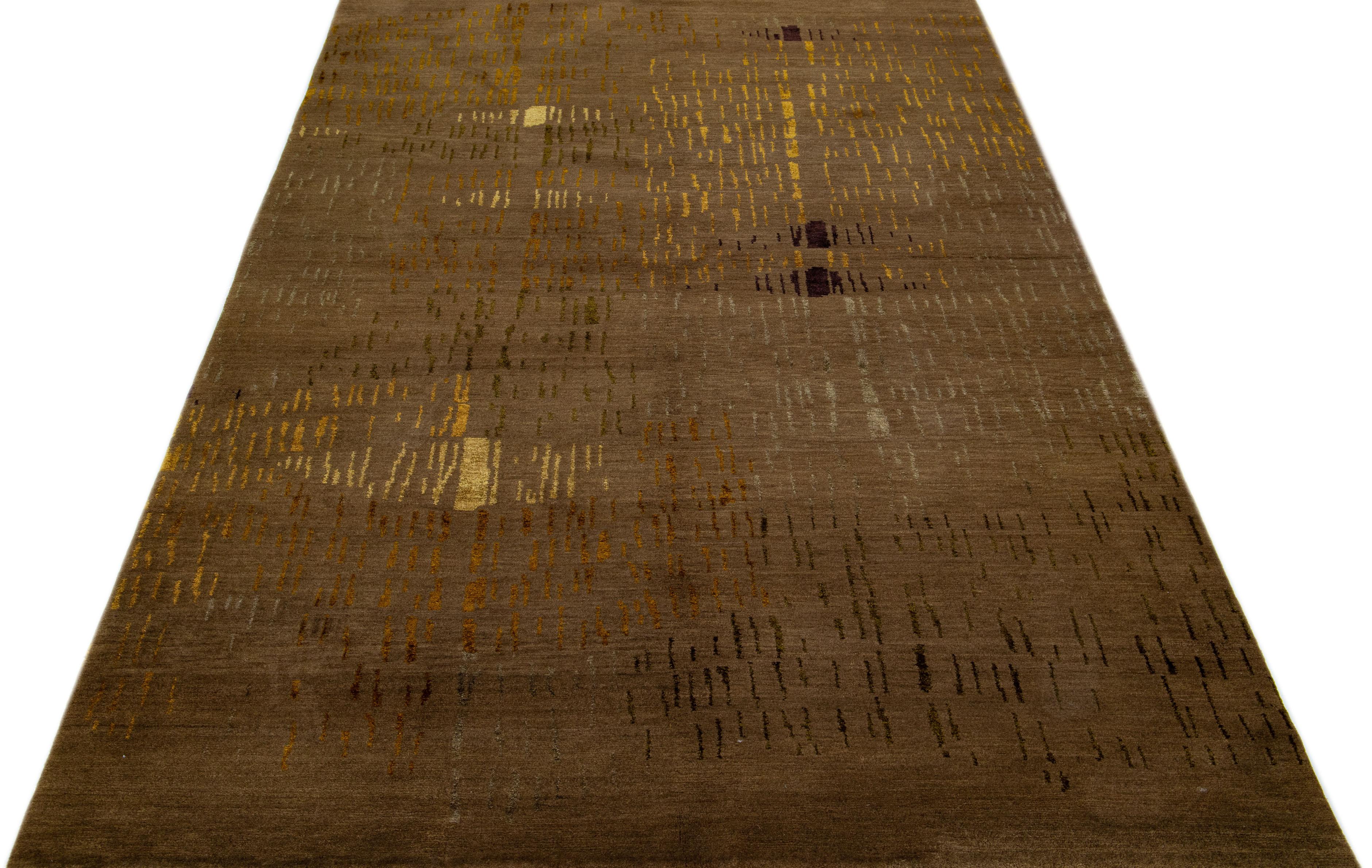 Dieser moderne nepalesische Teppich wurde kunstvoll aus hochwertigen Woll- und Seidenmaterialien gefertigt und zeigt ein raffiniertes abstraktes Muster in tiefen Brauntönen, das durch üppige schwarze und goldene Verzierungen elegant hervorgehoben