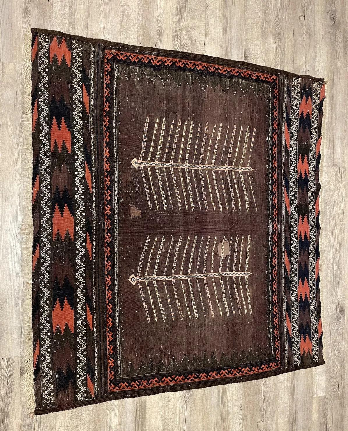 Ce tapis kilim afghan ancien, fait à la main et datant des années 1900, est un exemple captivant de l'artisanat traditionnel. Mesurant 106 cm de large et 120 cm de long, ce tapis en laine présente des motifs complexes qui ajoutent une touche de