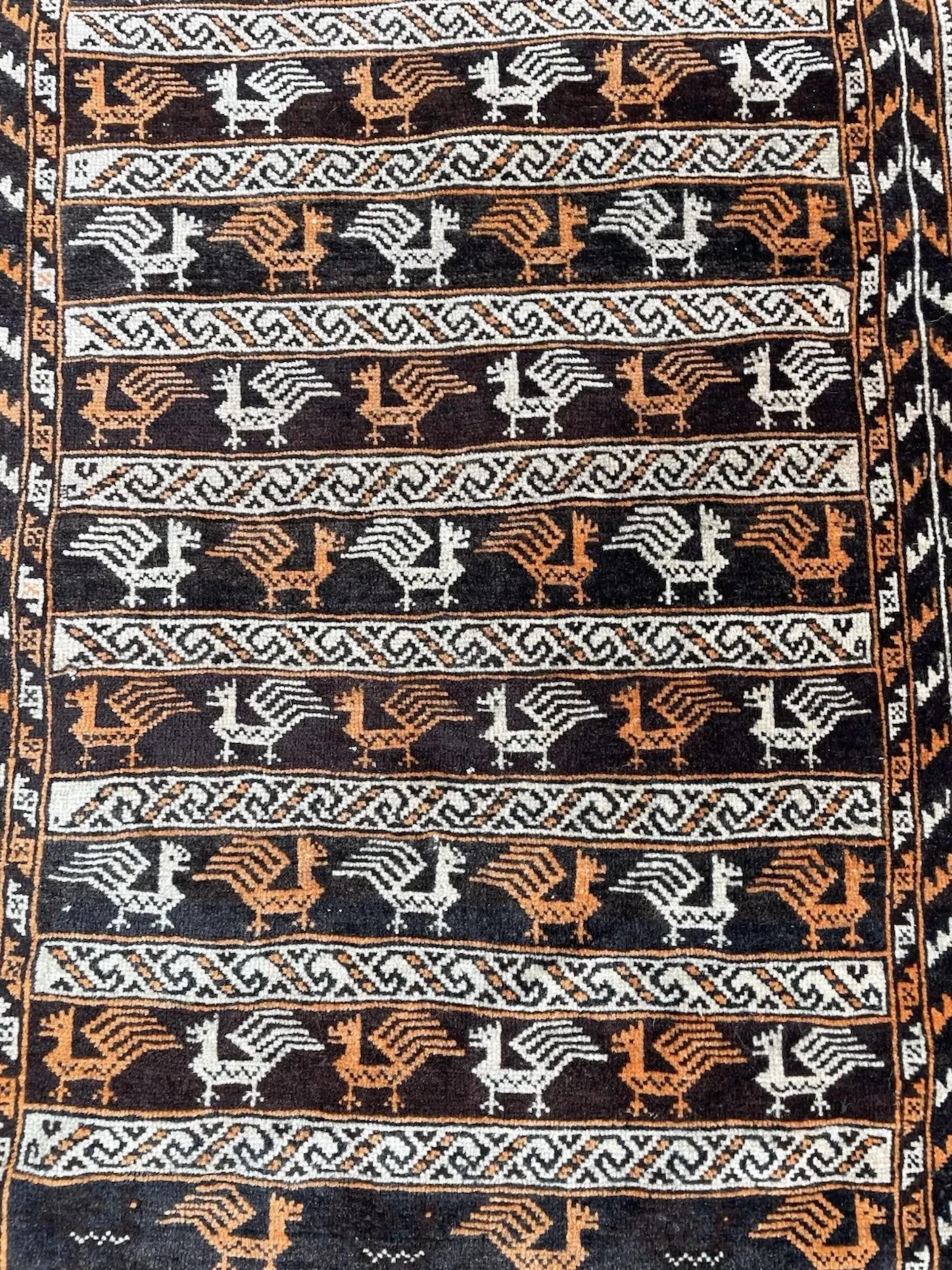 Questo squisito tappeto antico Baluch è un autentico pezzo di arte tribale, meticolosamente annodato a mano in Afghanistan e risalente agli anni '20 del secolo scorso. I tappeti Baluch sono molto ricercati dai collezionisti per la loro forte eredità