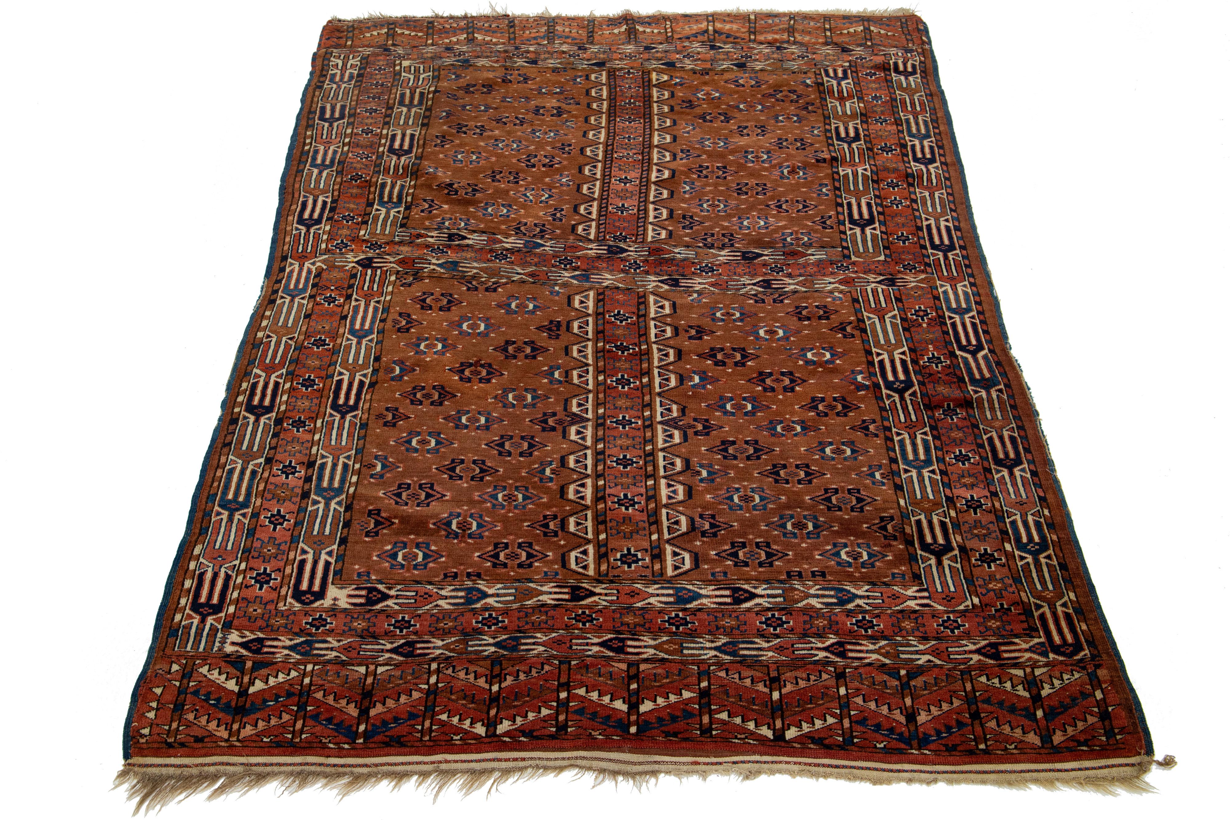 This antique Yamoud wool rug, with its medium brown color, stands out due to its impressive geometric design in shades of navy blue, bright ochre, and terracotta.

This rug measures 4'4