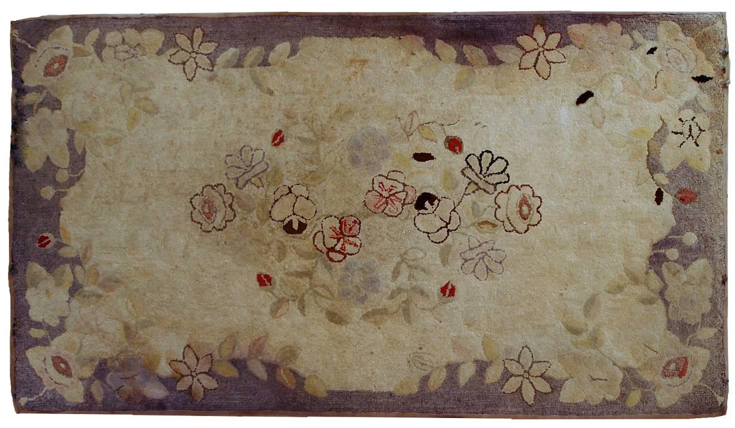Handmade antique American Primitive hooked rug in beige shade with abstract/floral design. The border is purple. It is in good condition, has minimal restorations on the ends.
 