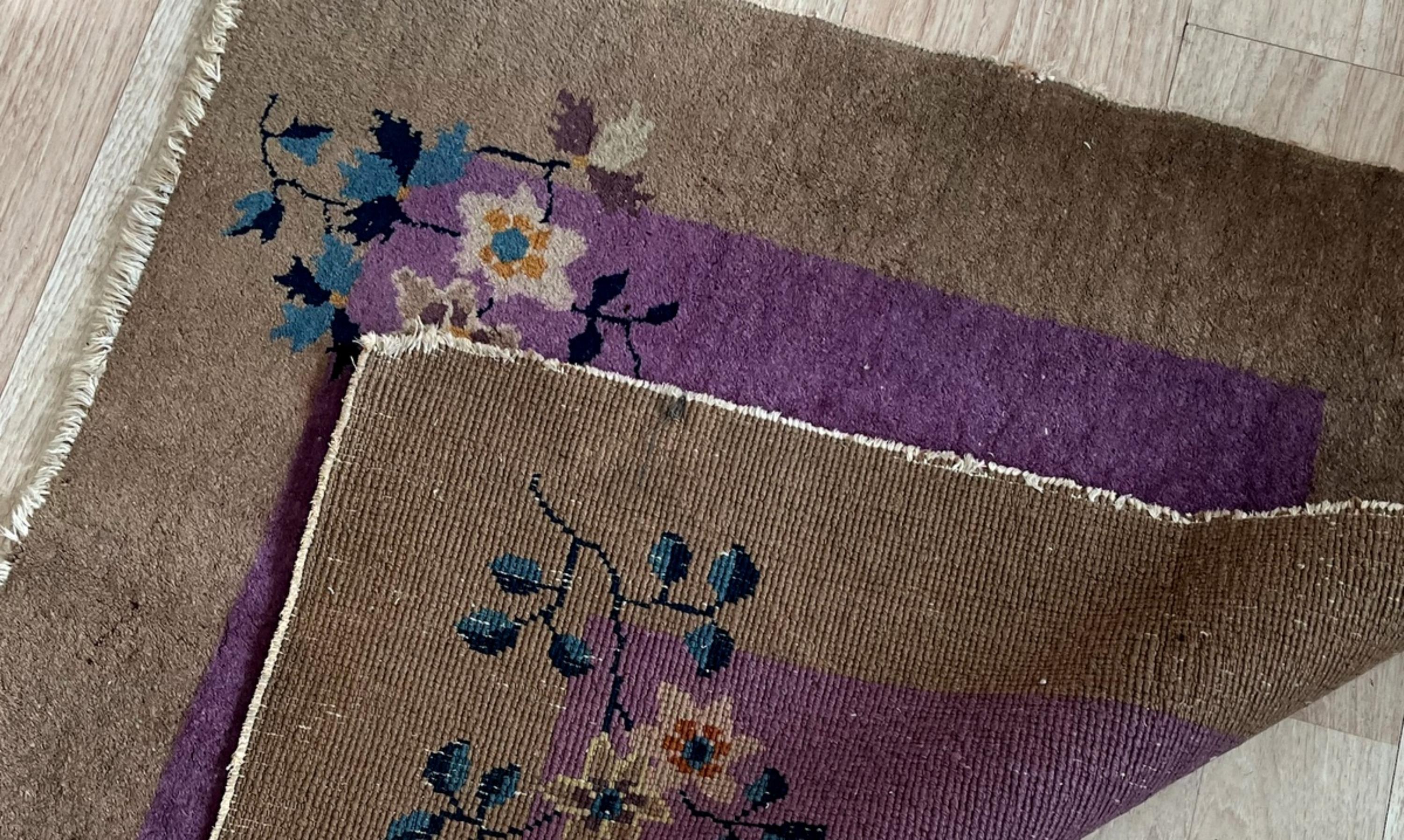 Ce tapis chinois antique Art Deco des années 1920, fait à la main, présente un riche champ violet encadré d'une bordure brune chaleureuse, créant un contraste saisissant. Les coins sont ornés de délicats motifs floraux dans des tons de jaune tendre,