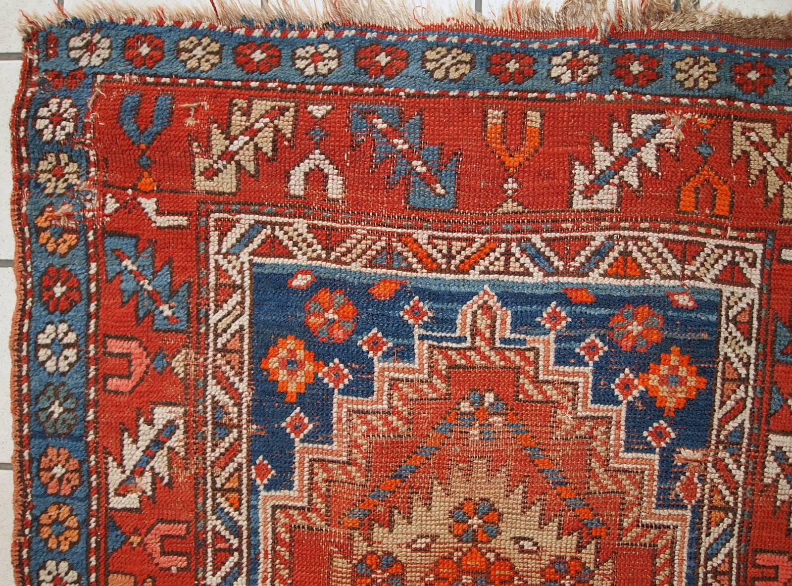 Handmade antique Caucasian runner in original distressed condition. The rug is in bright colors of red and blue. It has lots of age wear makes the base of the rug visible, but there no holes.
 