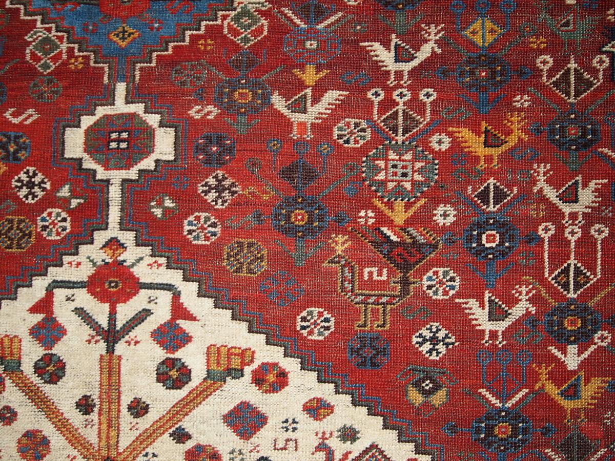 Khamseh carpet, late 19th century, three medium blue and ivory contiguous stepped hexagons on a red field displaying polychrome stylized birds, 