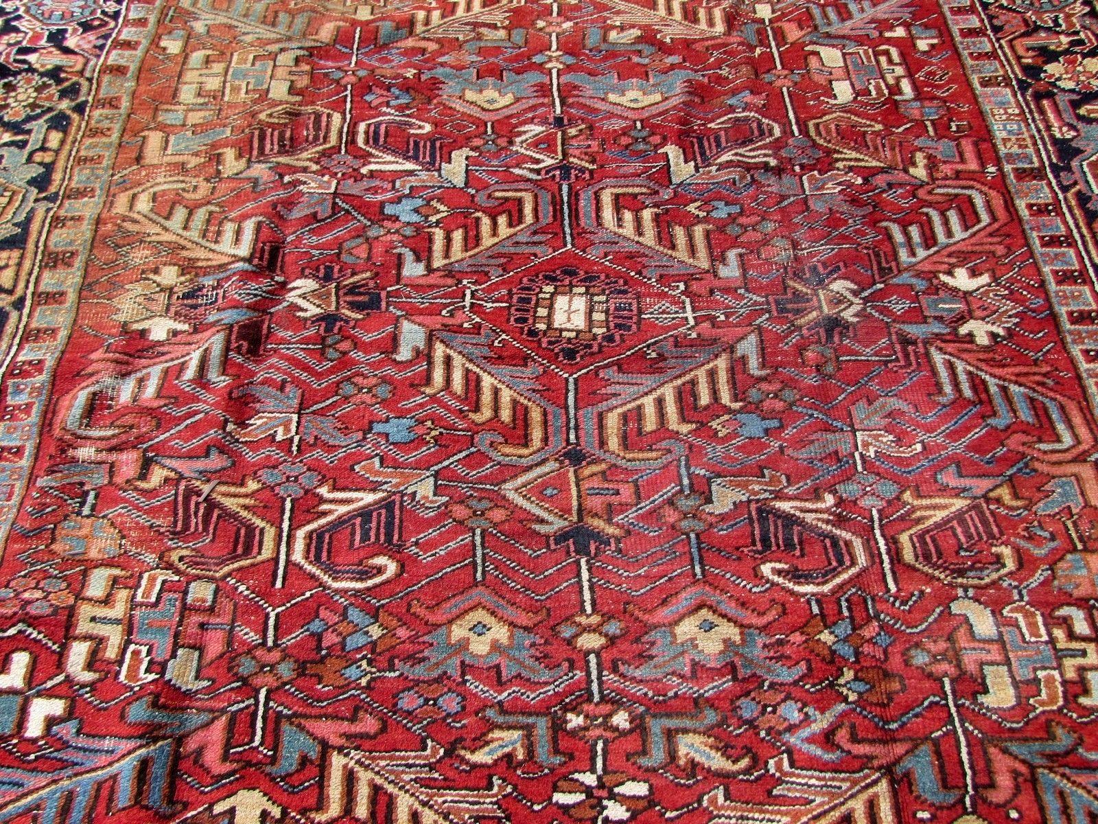 Handmade antique Persian Heriz rug in red wool. The rug is from the beginning of 20th century, it is in original condition, it has some age wear, low pile and yellow stain on one side.

-Condition: Distressed, yellow stain on one side,

-circa