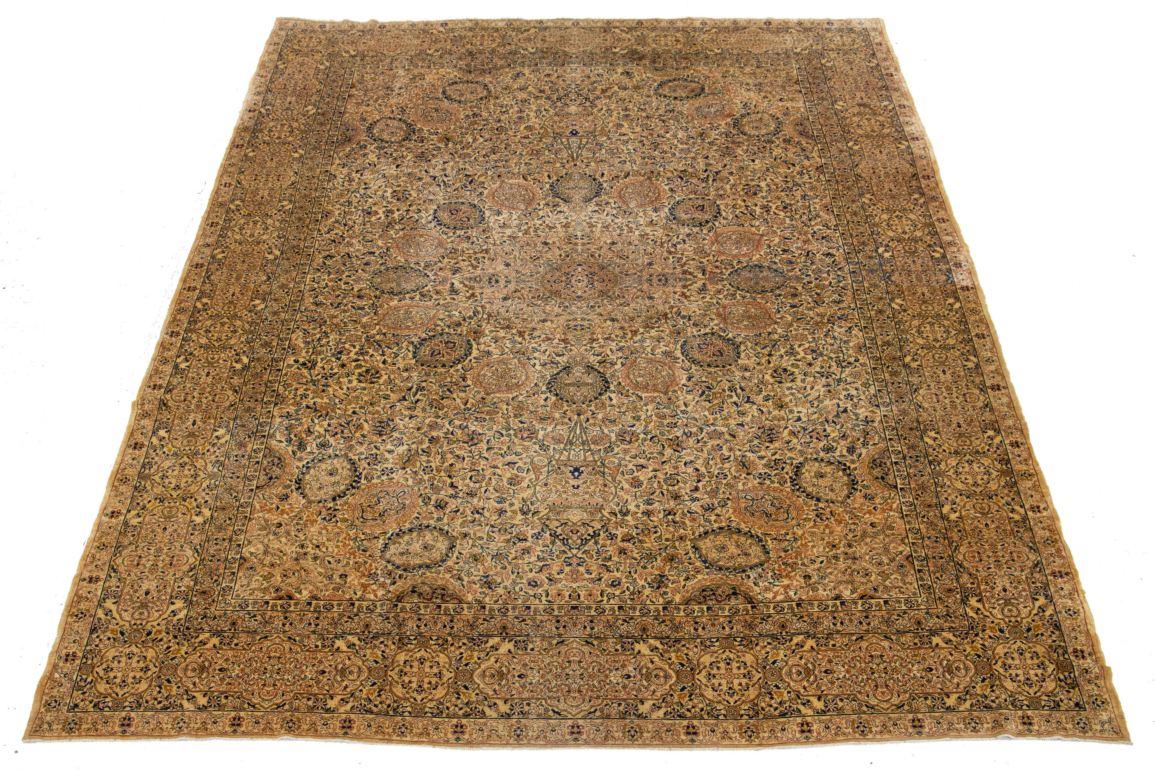 Cette pièce est une antiquité des années 1900. Il présente un motif bleu, verge d'or et rouille sur un champ beige-tan. Il présente une large double bordure avec un motif complexe.

Ce tapis mesure 10'6