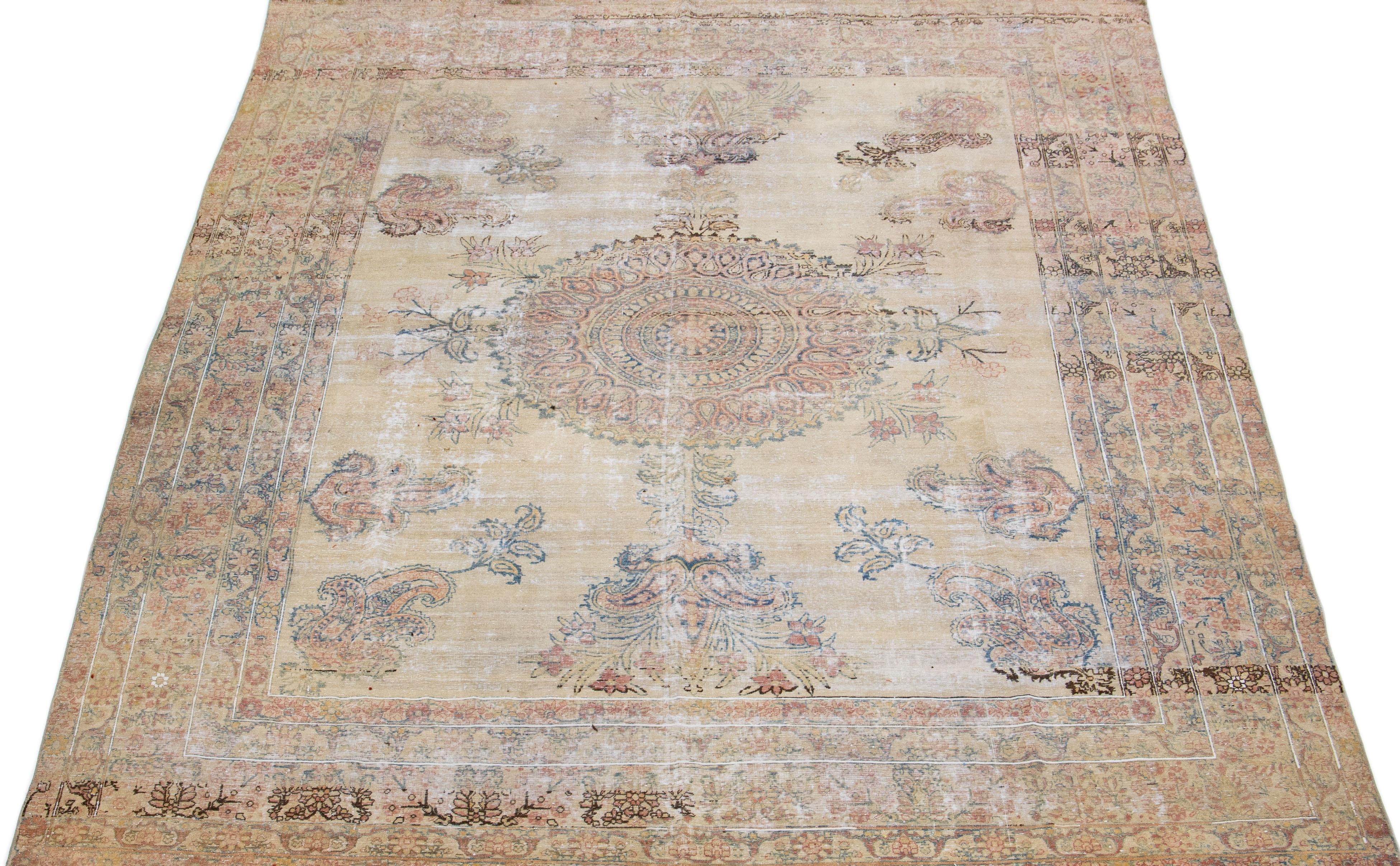 Beautiful antique Kerman hand-knotted wool rug with a tan field. This Persian rug has rust & blue accents in a gorgeous medallion floral pattern.

This rug measures: 8'6