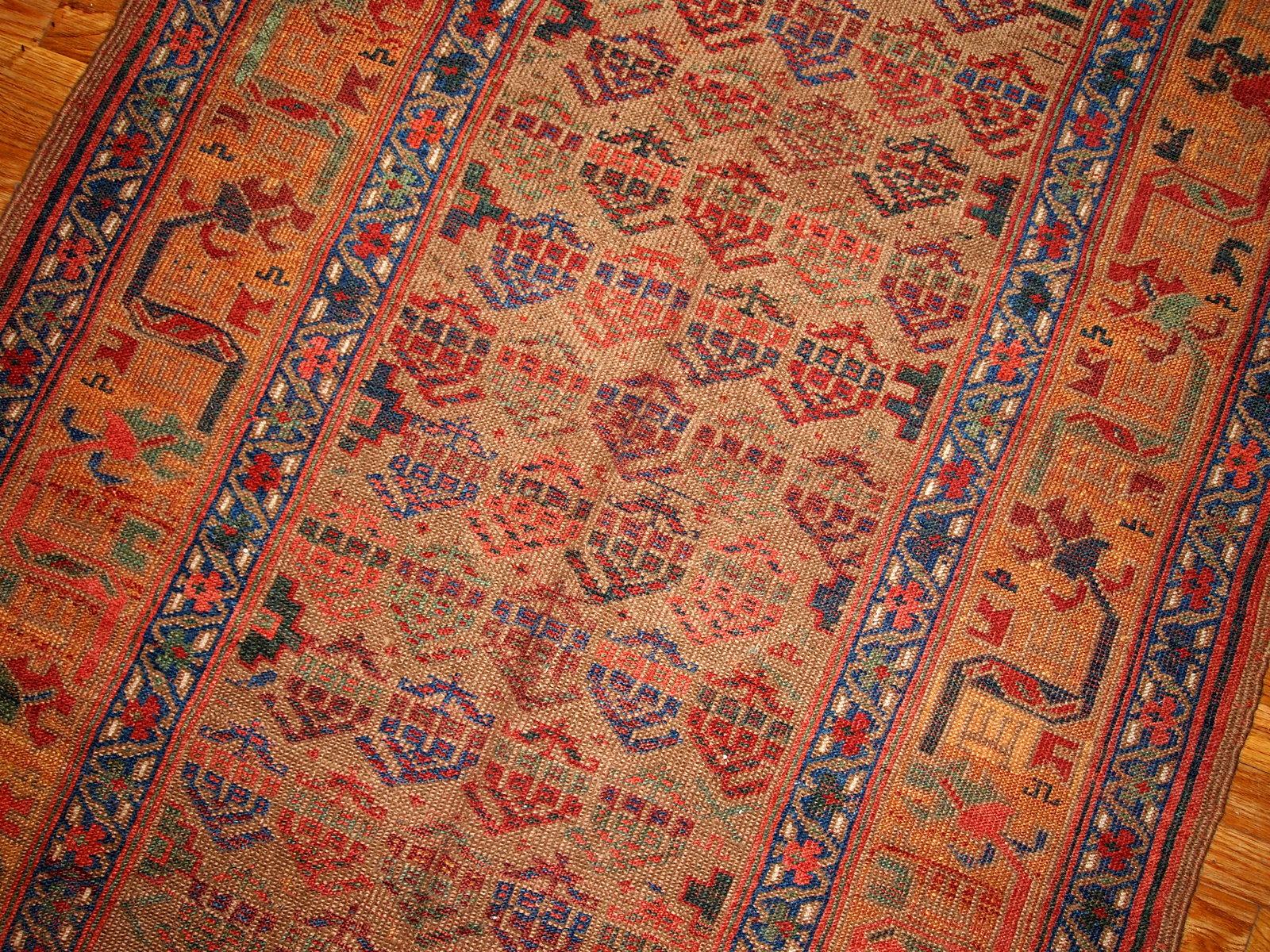 Alfombra antigua de estilo kurdo de diseño tradicional, en tonos verde oliva y amarillo. La alfombra es de finales del siglo XIX, en buen estado.